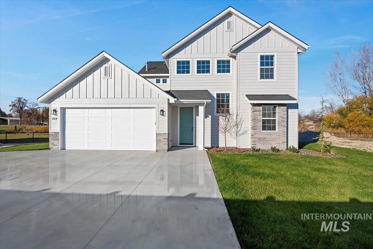View of front of home with board and batten siding, a front lawn, concrete driveway, and an attached garage