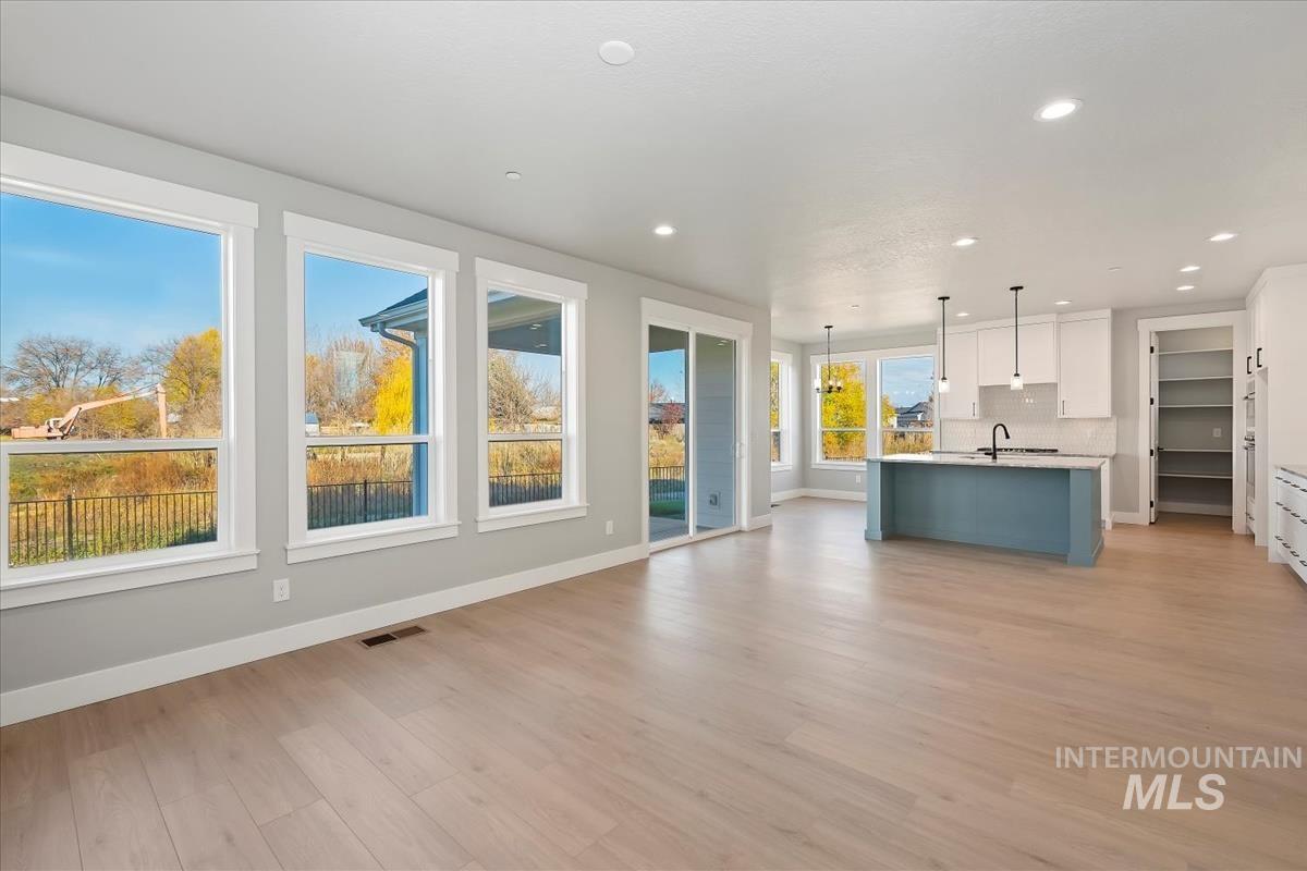 Kitchen with white cabinetry, hanging light fixtures, light wood-type flooring, open floor plan, and recessed lighting