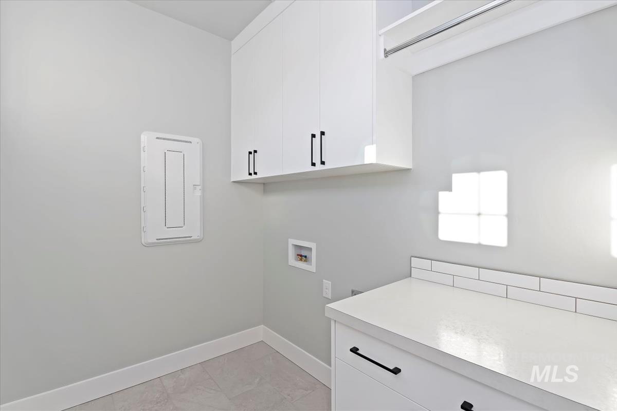 Laundry room with washer hookup, cabinet space, and electric panel