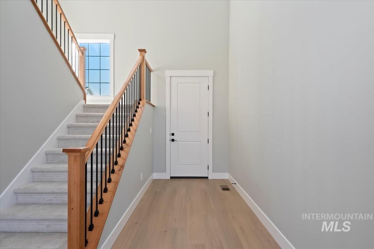 Staircase with wood finished floors and a towering ceiling