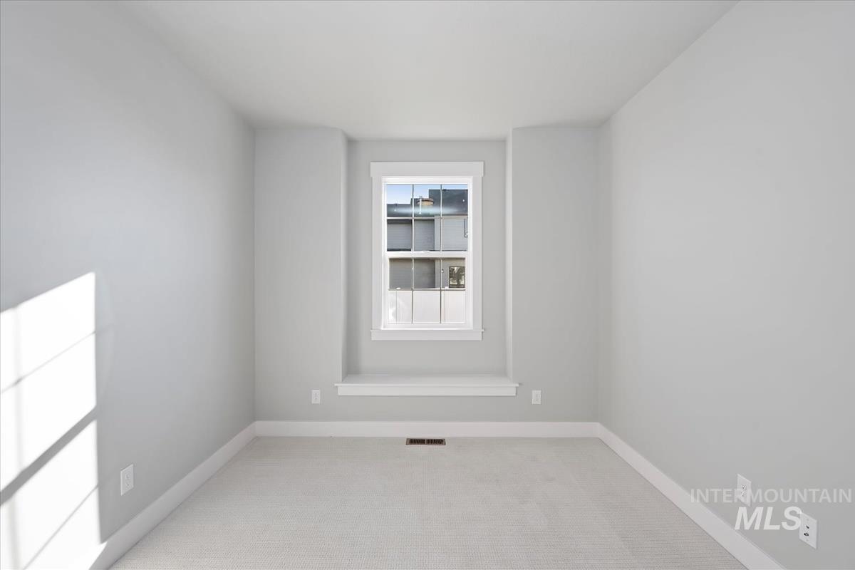 Empty room with light colored carpet and baseboards