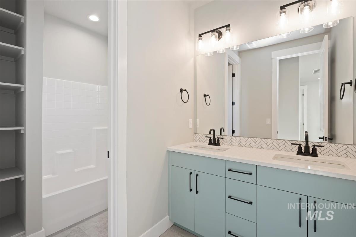 Bathroom with double vanity, recessed lighting, and light tile patterned flooring