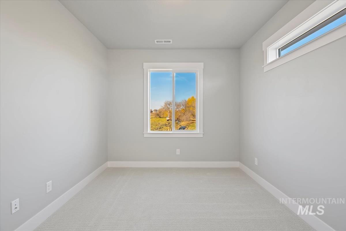 Empty room featuring light colored carpet and baseboards