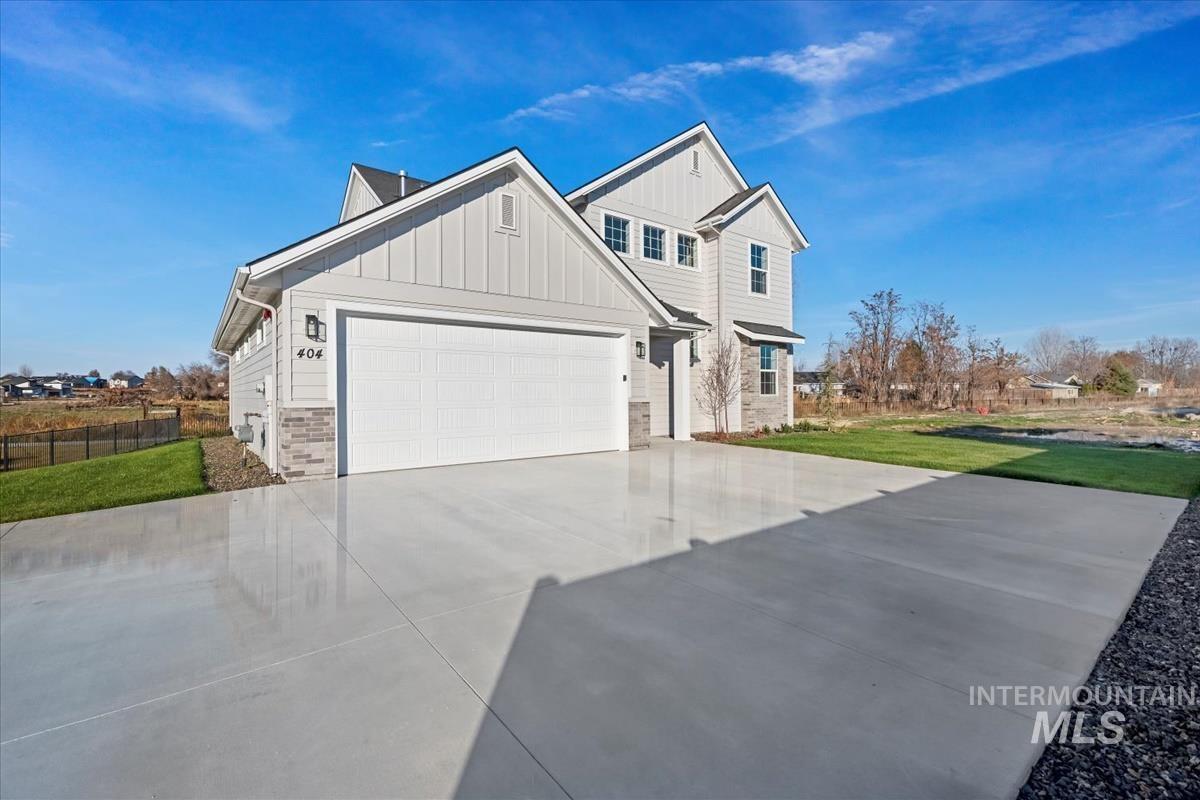 View of front of home featuring board and batten siding, stone siding, concrete driveway, and an attached garage