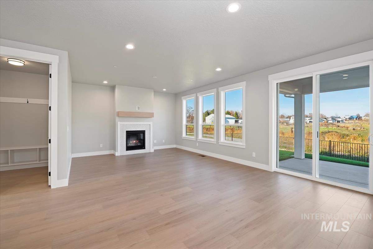 Unfurnished living room with light wood-type flooring, recessed lighting, and a glass covered fireplace
