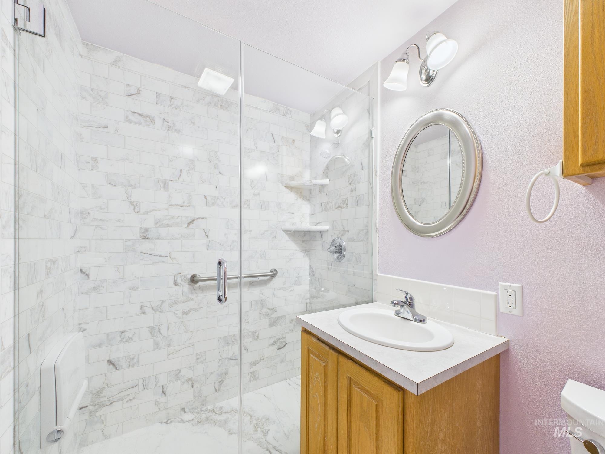 Bathroom with vanity, a shower stall, and a textured wall