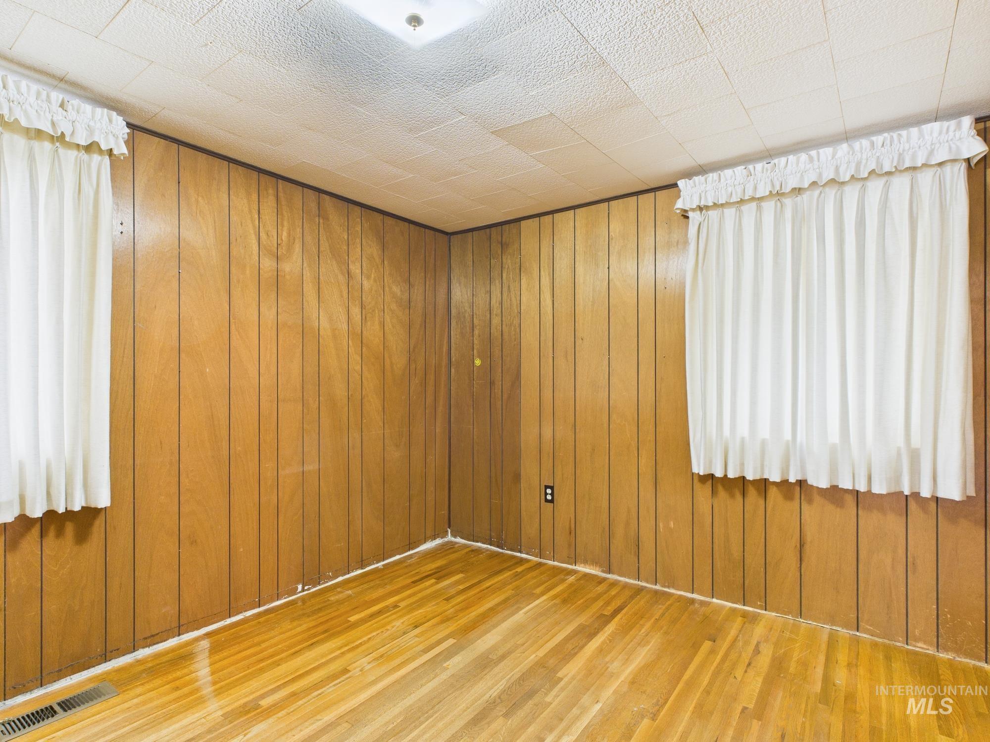 Unfurnished room featuring wooden walls and wood finished floors
