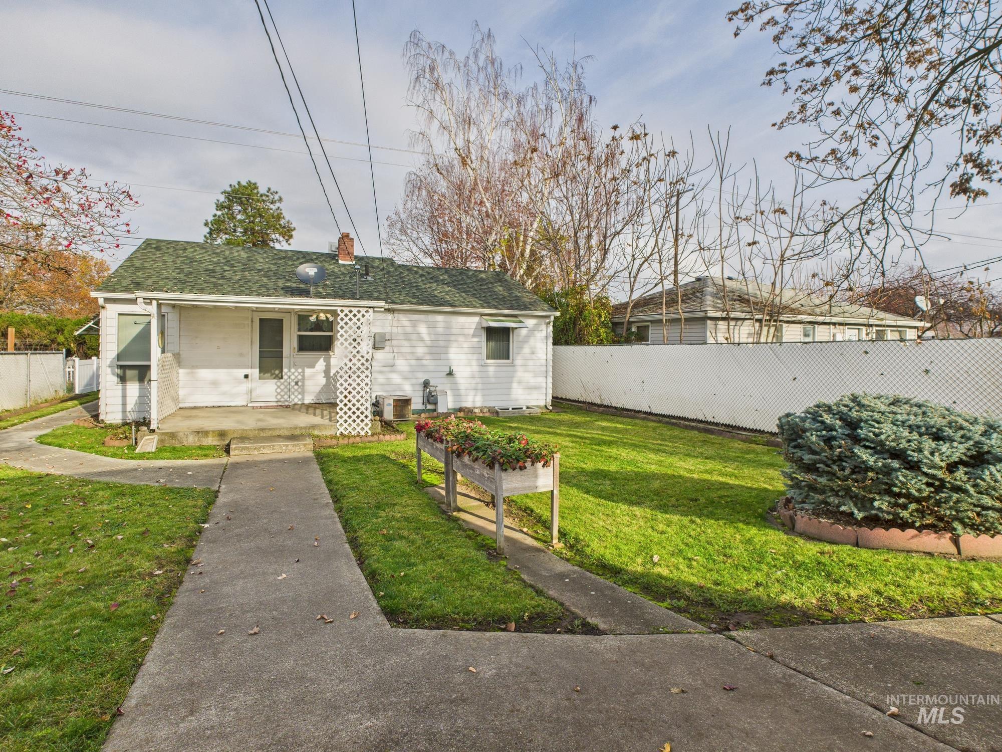 View of front facade with a fenced backyard, a chimney, and roof with shingles