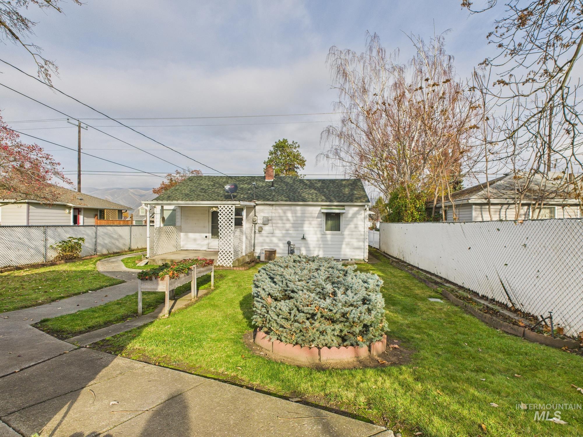 Back of house featuring a fenced backyard, a chimney, and covered porch
