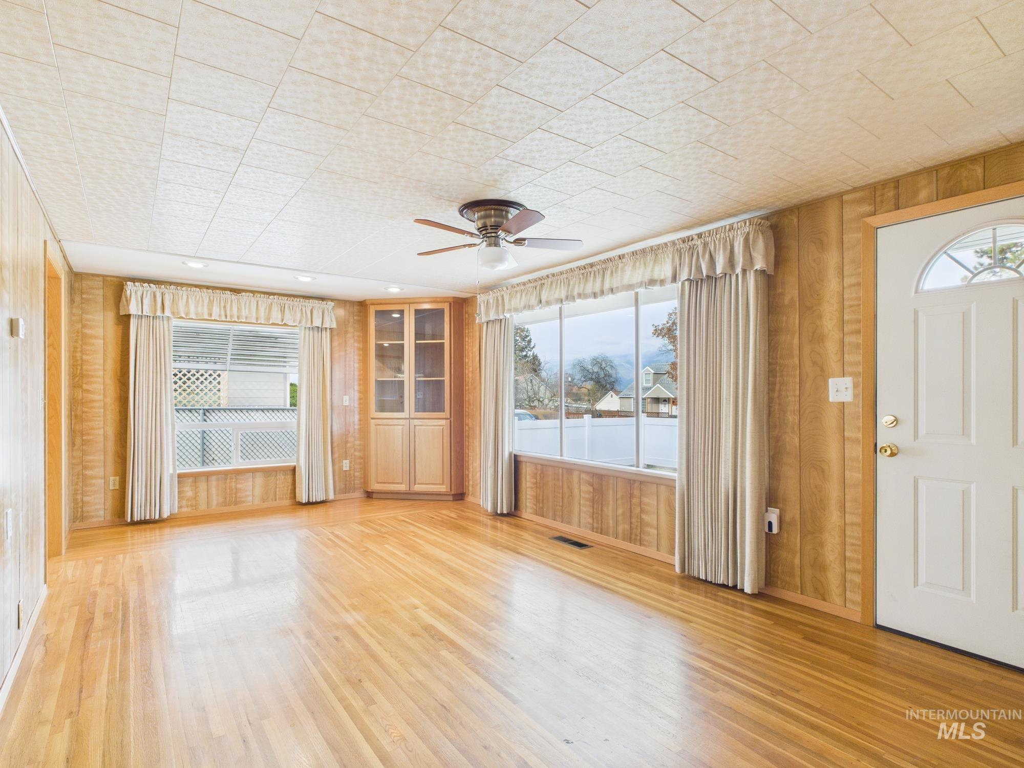 Foyer featuring wooden walls, plenty of natural light, ceiling fan, and light wood-style floors