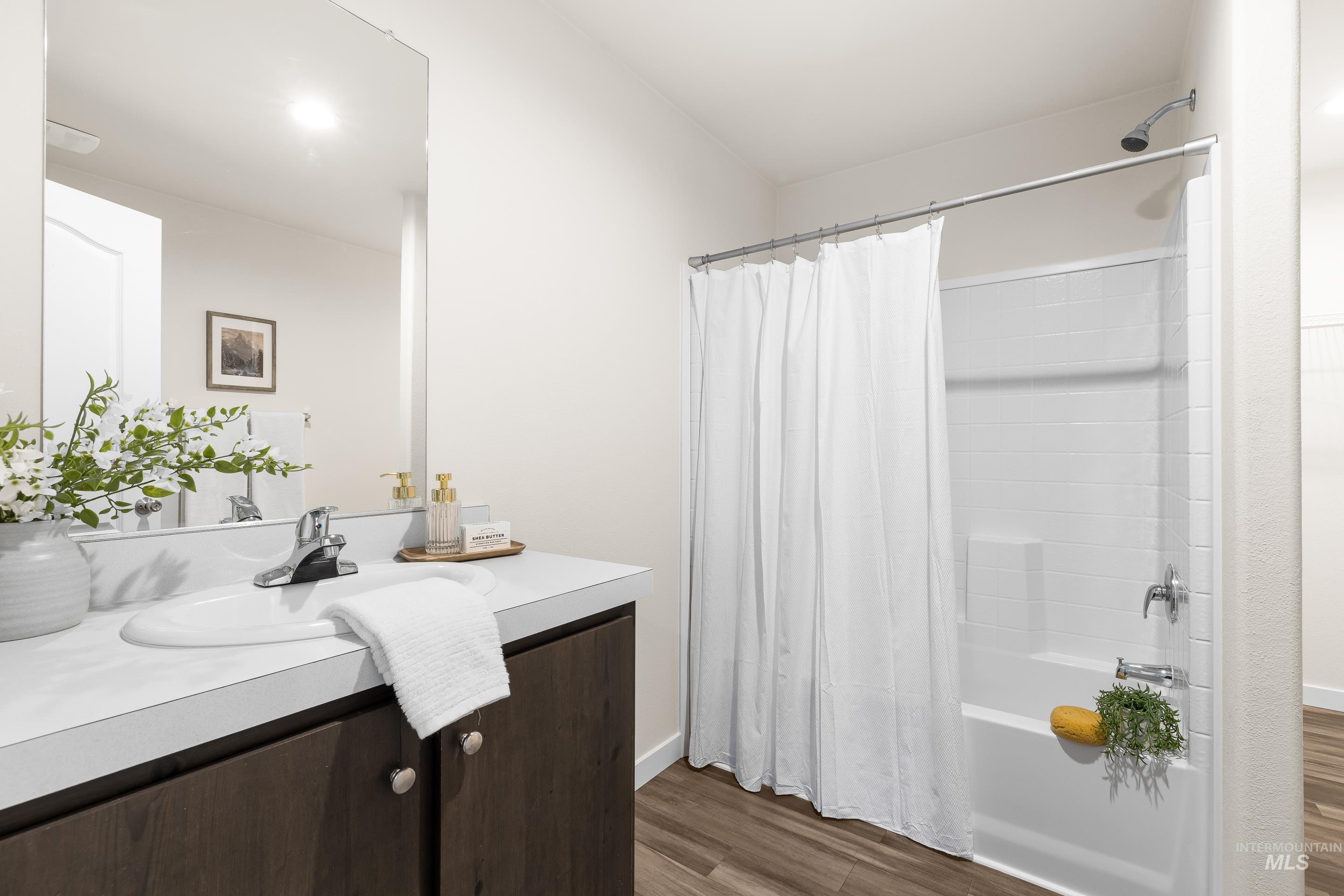 Bathroom featuring shower / tub combo with curtain, vanity, and dark wood-type flooring