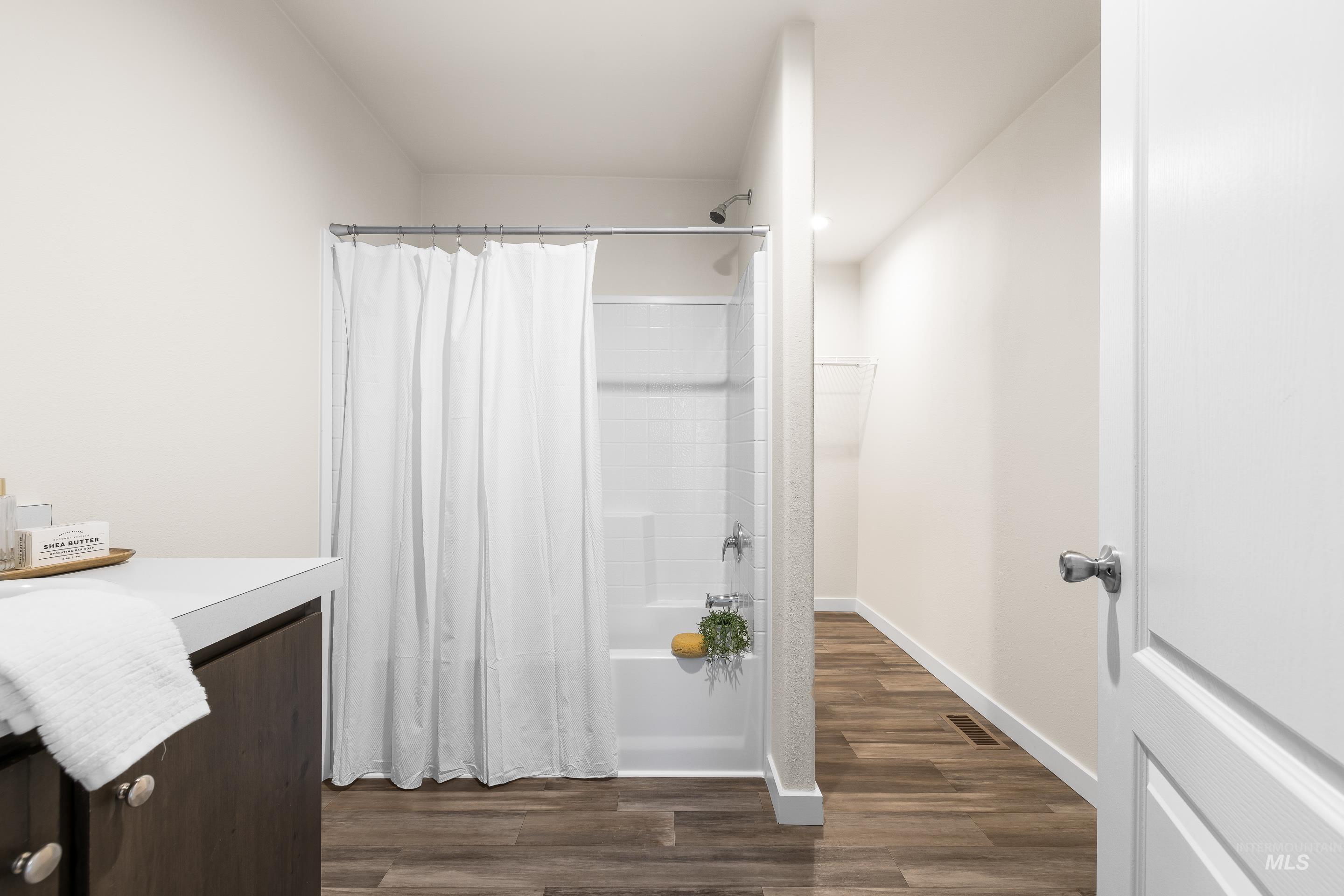 Bathroom with shower / bath combo with shower curtain, vanity, and dark wood finished floors