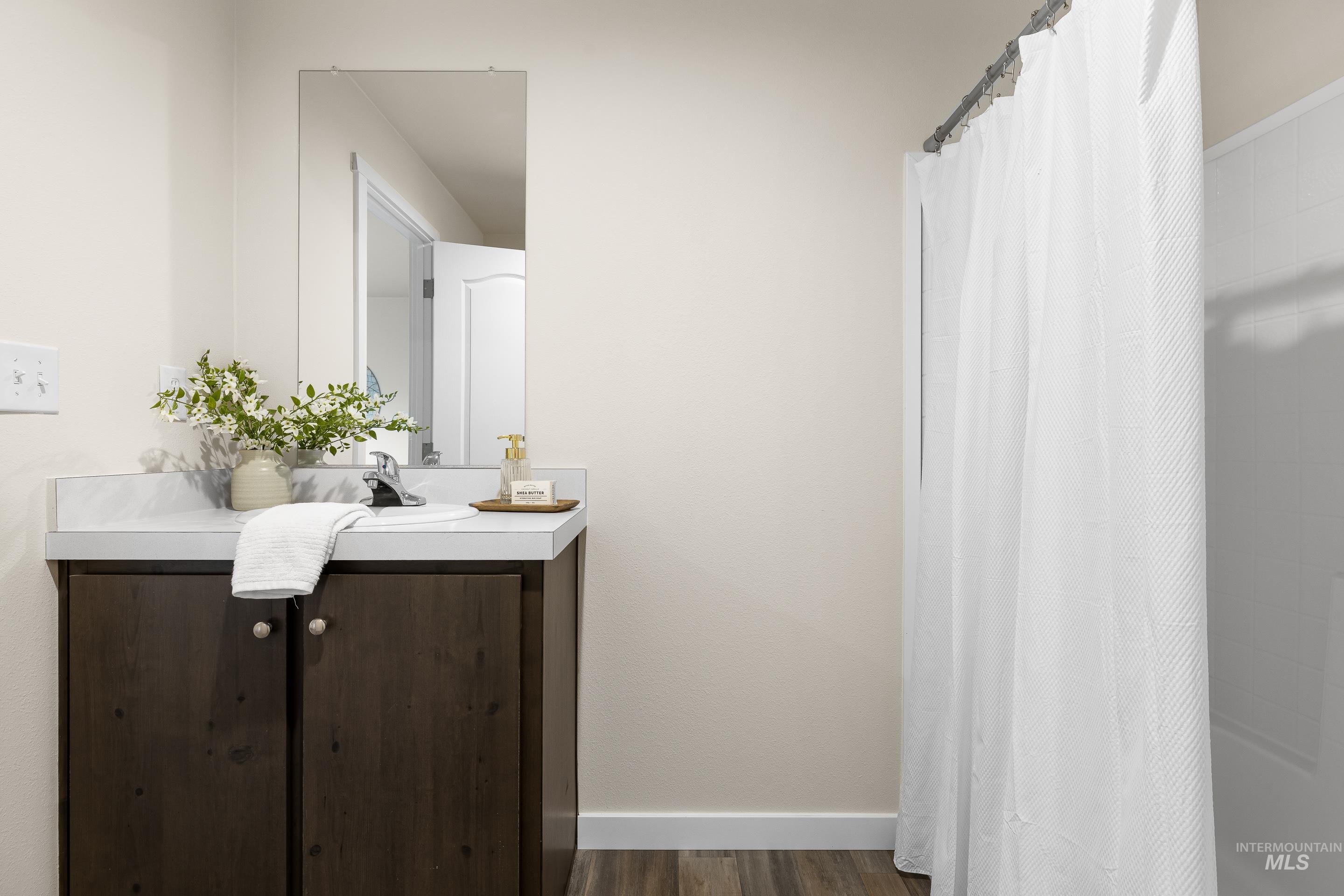 Bathroom featuring vanity, a shower with shower curtain, and dark wood finished floors