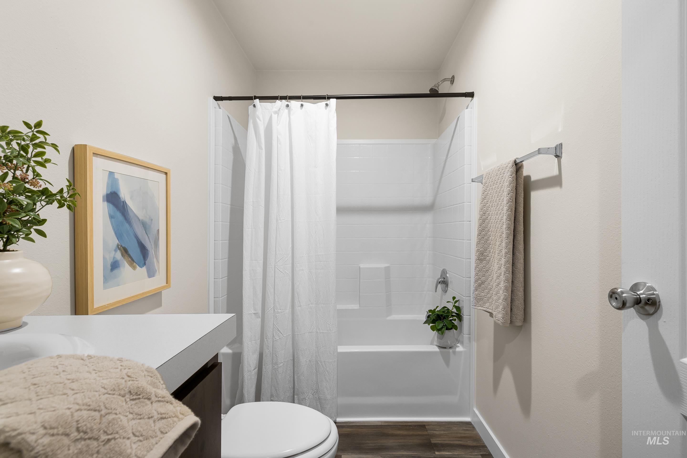 Bathroom featuring vanity, shower / bathtub combination with curtain, and dark wood-style floors