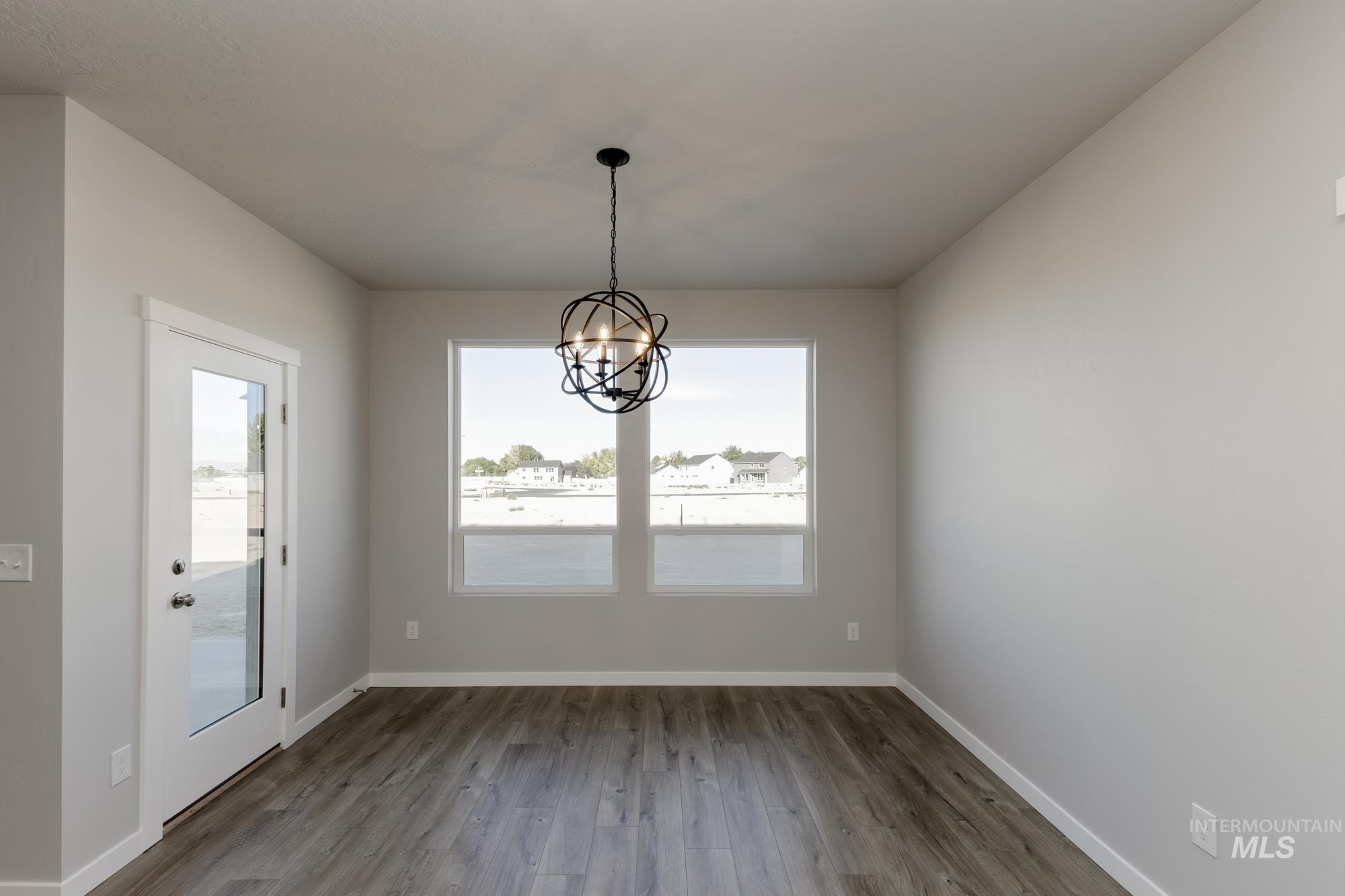 Unfurnished dining area featuring dark wood finished floors and a chandelier