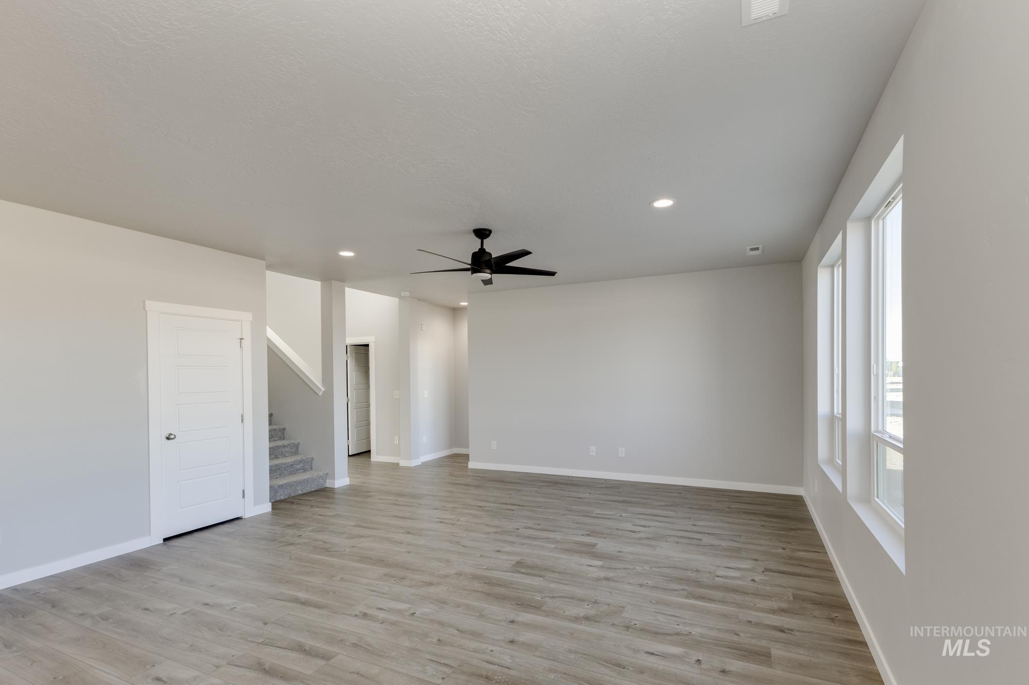 Empty room with stairway, recessed lighting, light wood-type flooring, and ceiling fan
