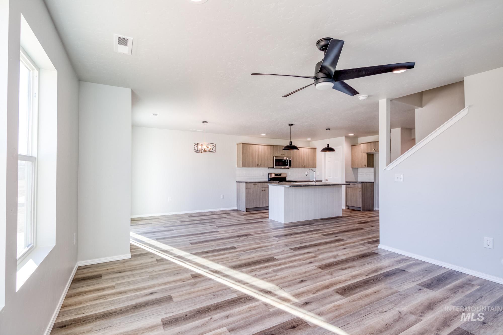 Unfurnished living room featuring light wood-style floors, a chandelier, and ceiling fan