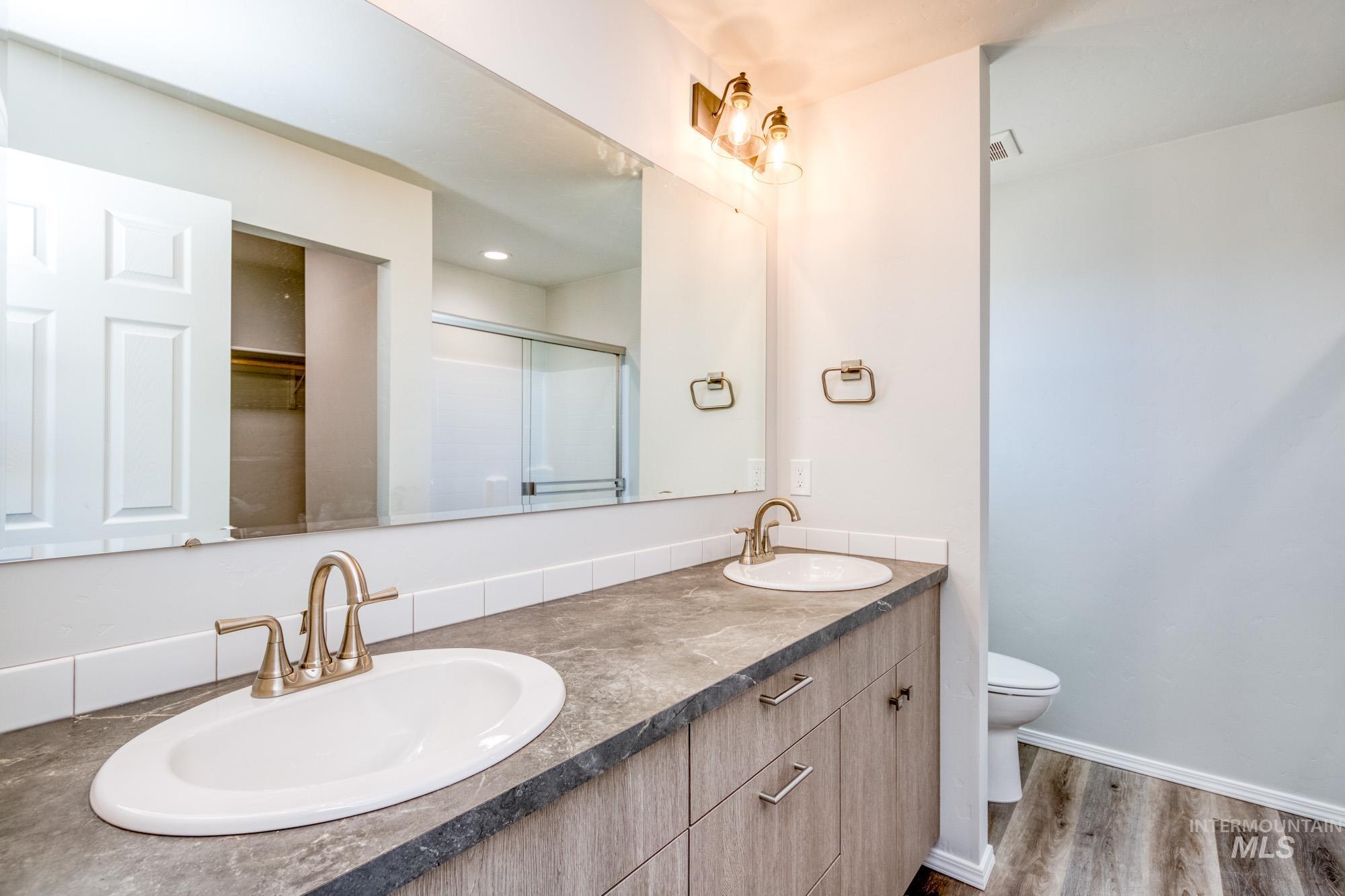 Full bathroom with a stall shower, double vanity, and light wood-type flooring