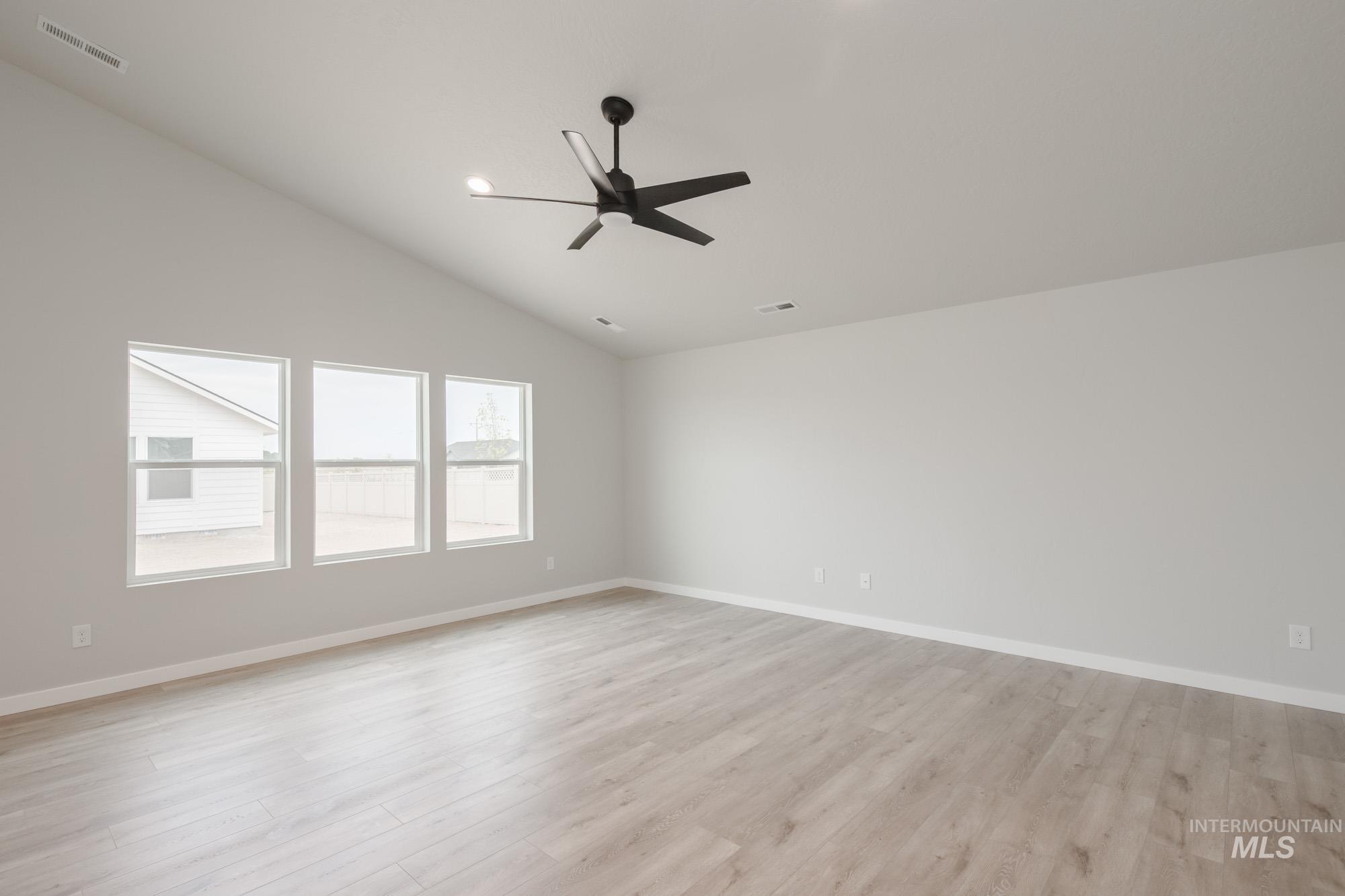 Spare room featuring vaulted ceiling, light wood-type flooring, ceiling fan, and recessed lighting