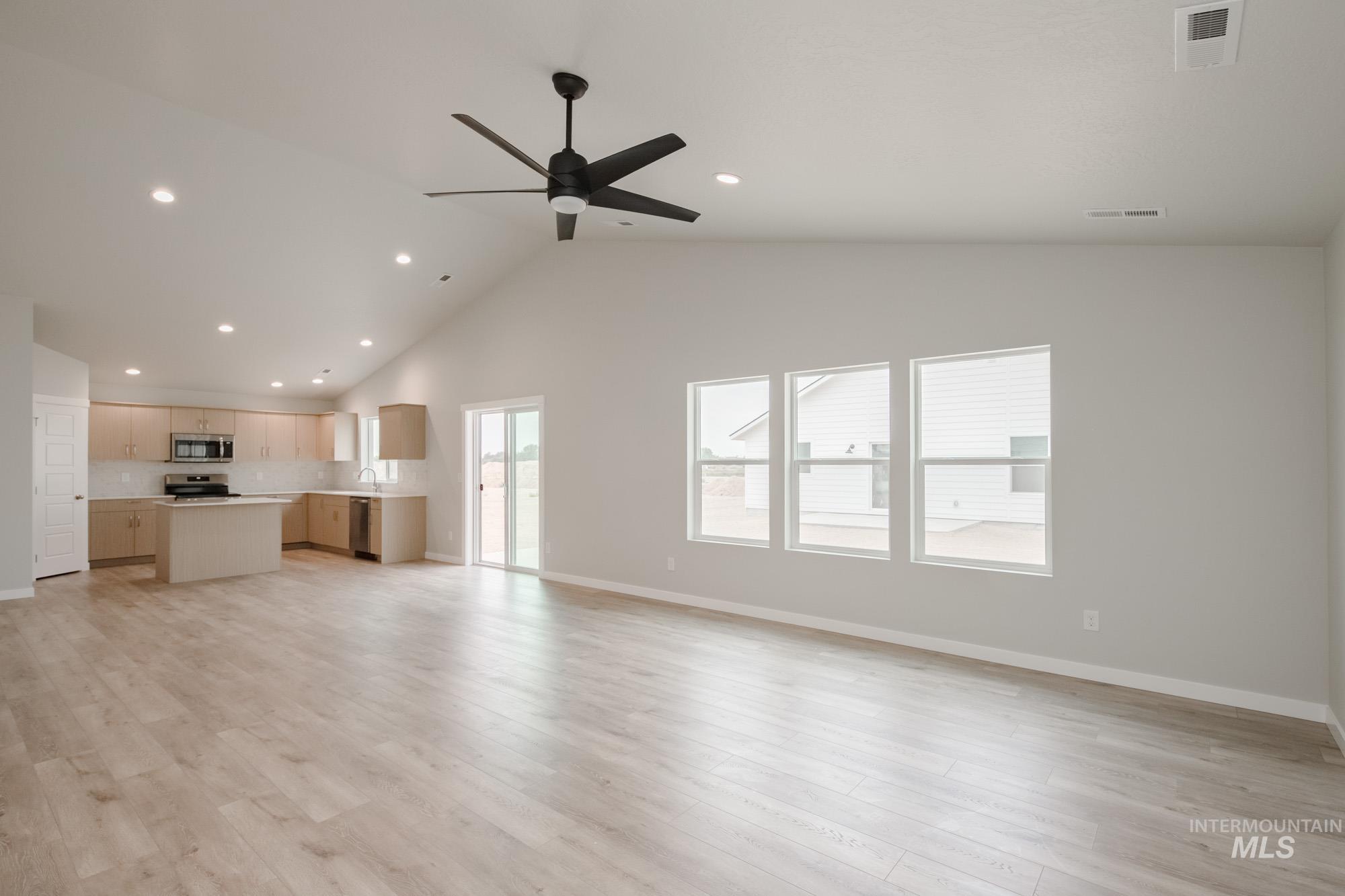 Unfurnished living room featuring high vaulted ceiling, light wood-style flooring, ceiling fan, and recessed lighting