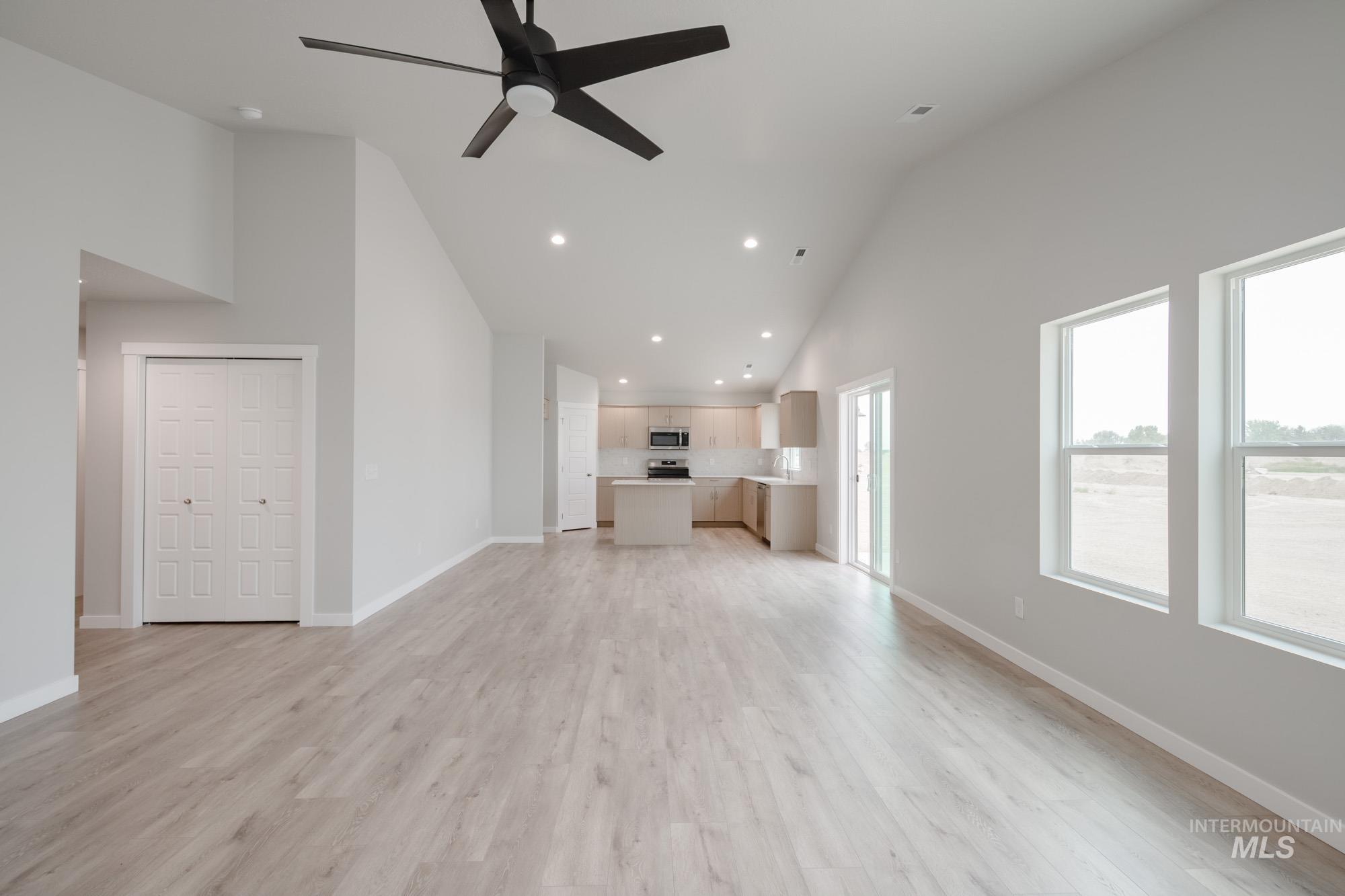 Unfurnished living room with high vaulted ceiling, recessed lighting, a ceiling fan, and light wood-type flooring