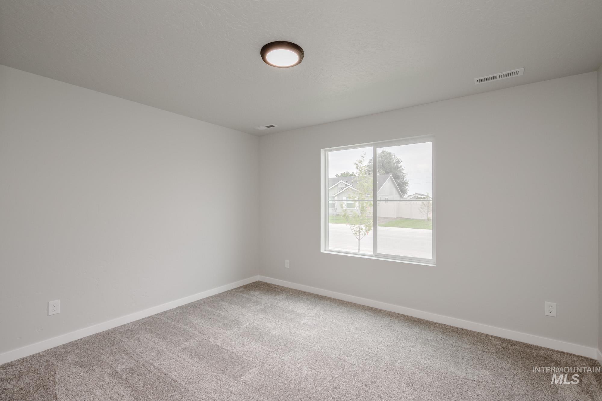 Spare room featuring light carpet and baseboards