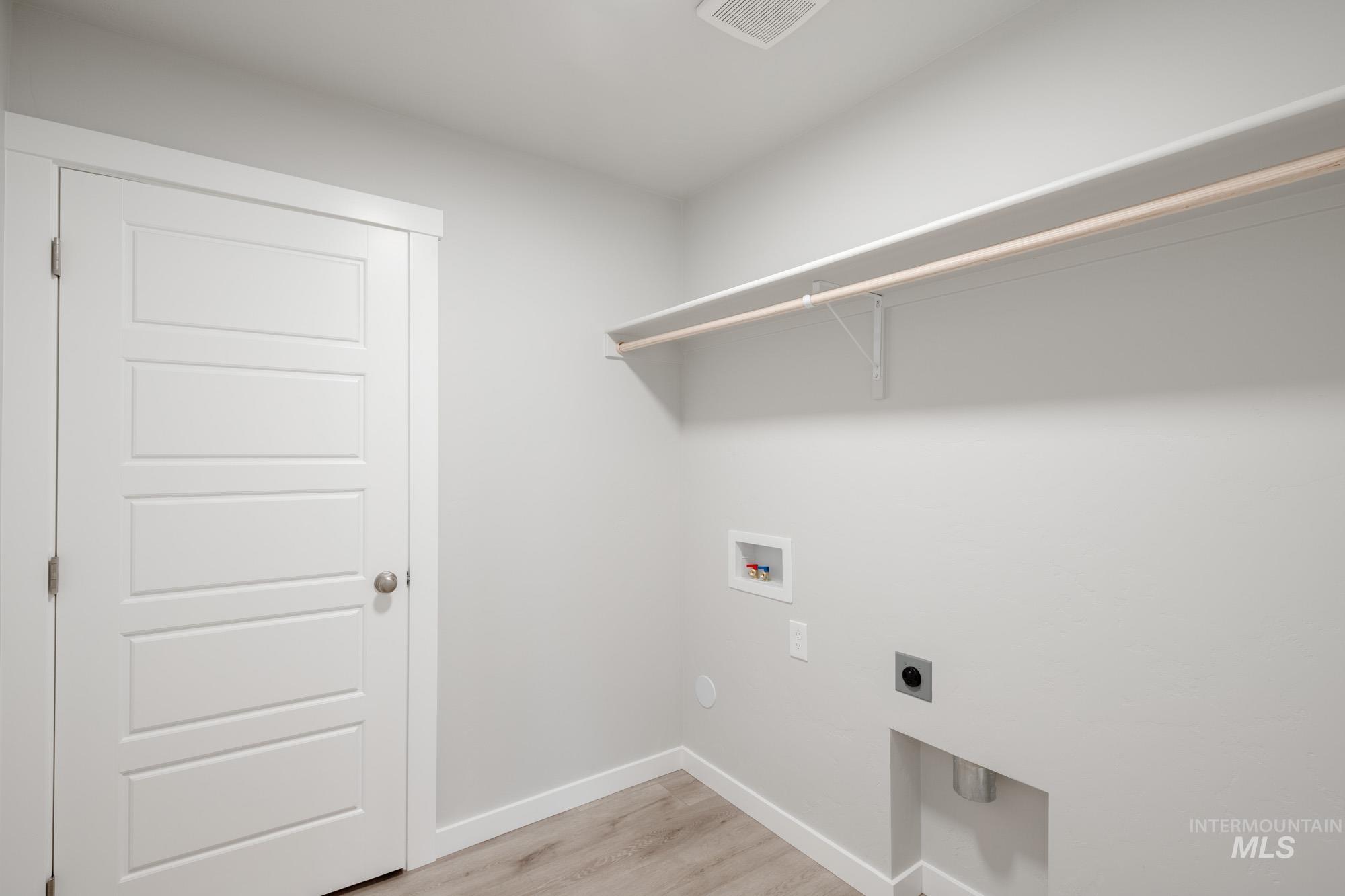 Laundry area with light wood-style flooring, hookup for a washing machine, and hookup for an electric dryer
