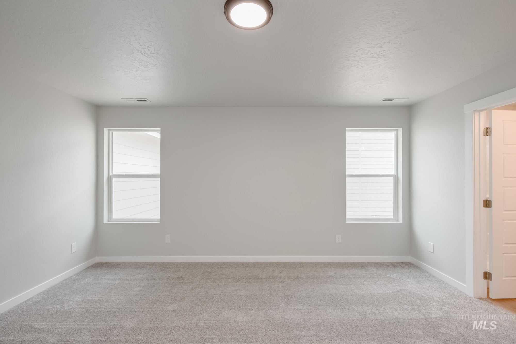 Spare room with a textured ceiling and light colored carpet