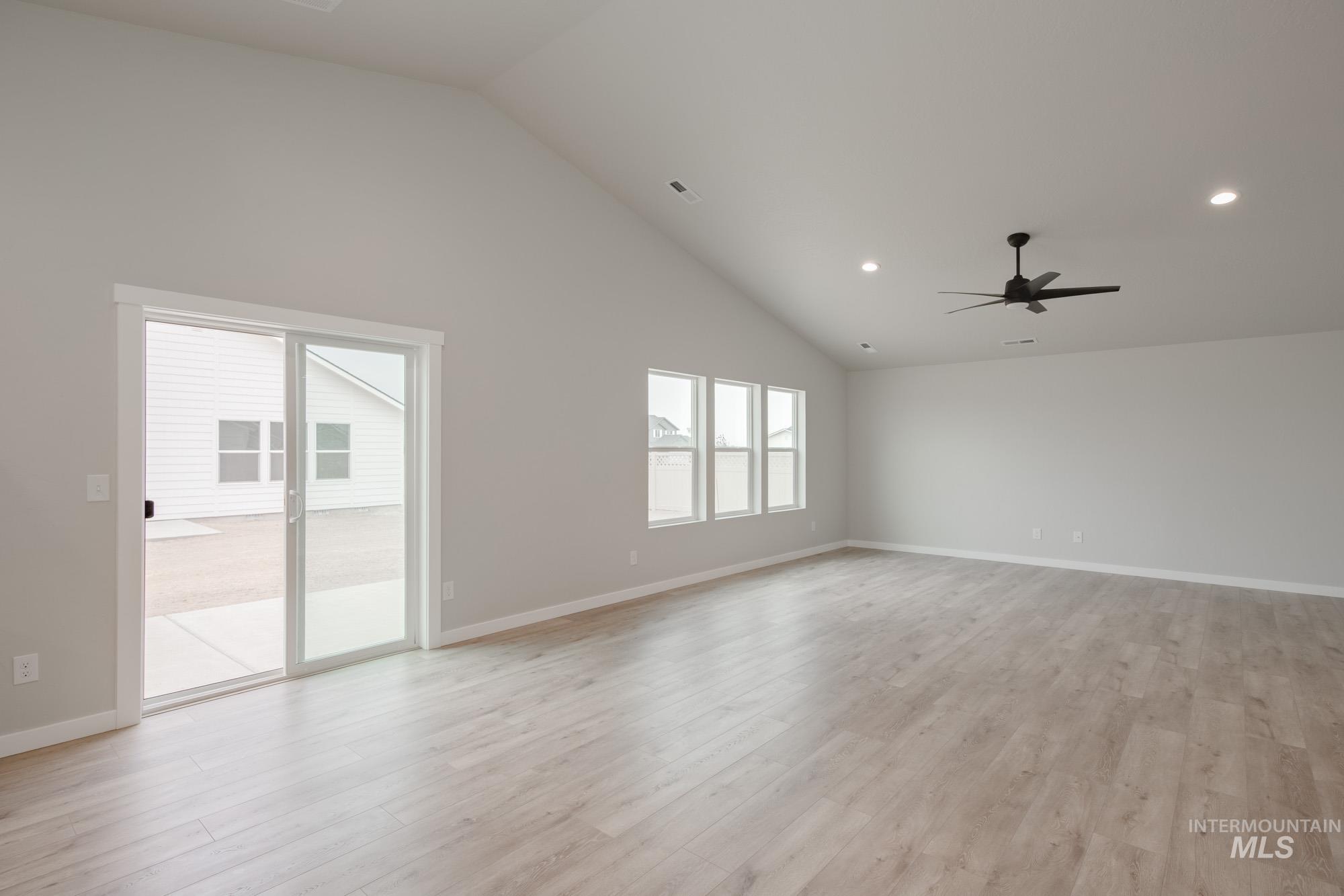 Empty room featuring high vaulted ceiling, light wood-style floors, recessed lighting, and ceiling fan