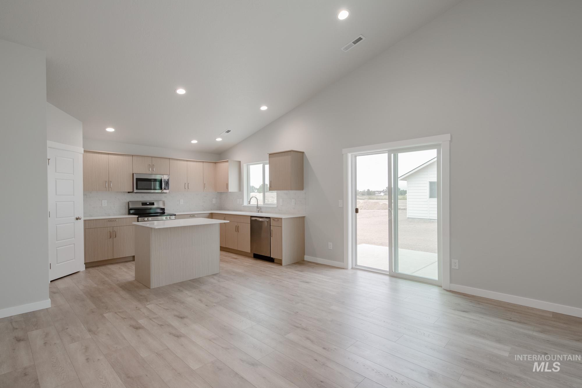 Kitchen featuring backsplash, recessed lighting, a center island, appliances with stainless steel finishes, and high vaulted ceiling