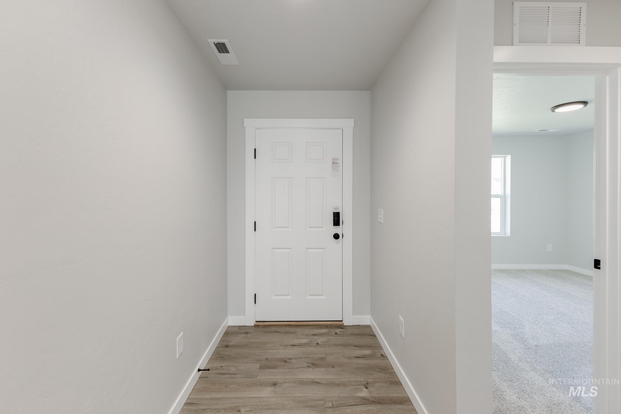 Doorway featuring baseboards and wood finished floors