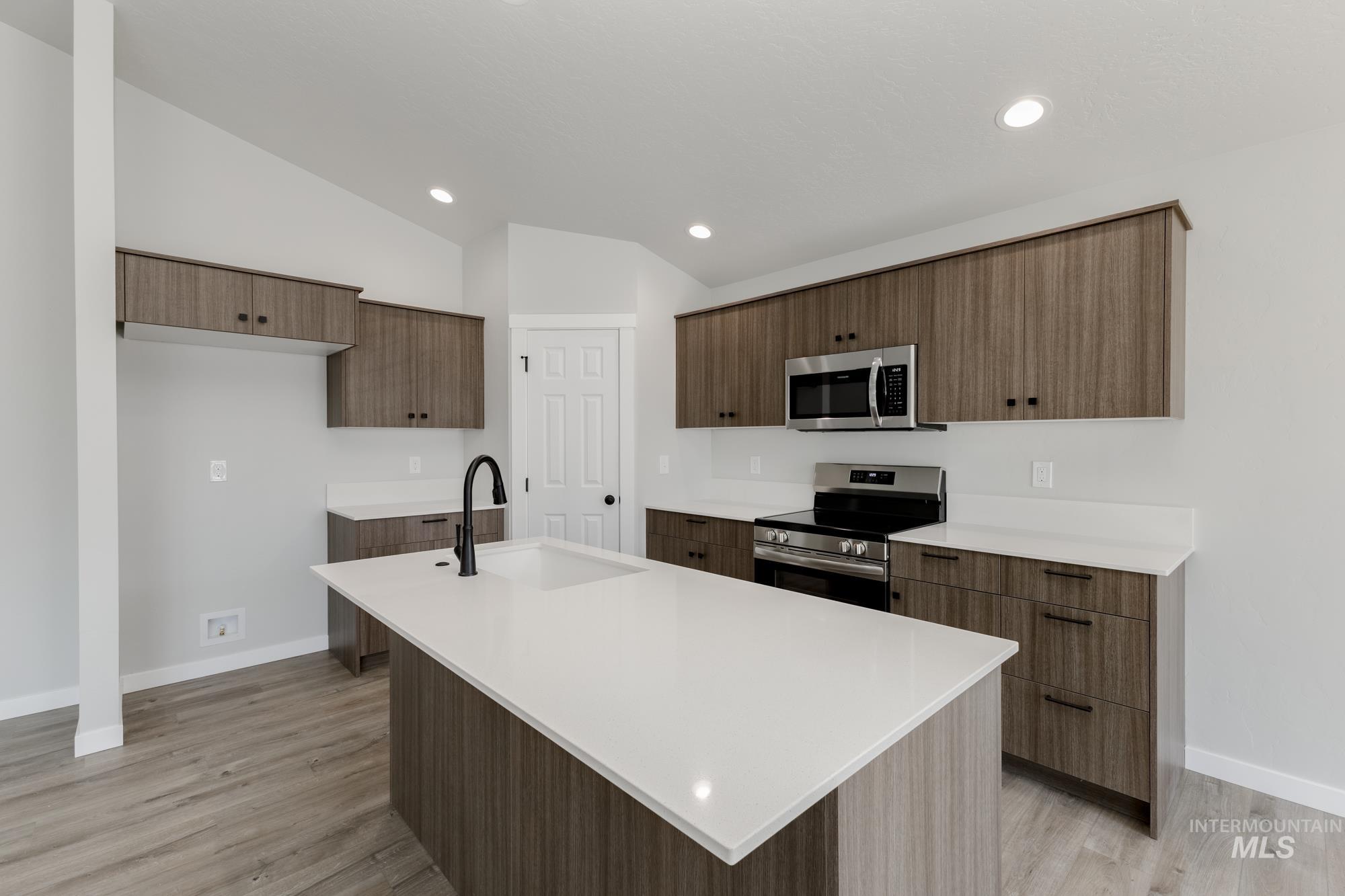 Kitchen featuring appliances with stainless steel finishes, modern cabinets, a kitchen island with sink, light wood-style flooring, and recessed lighting