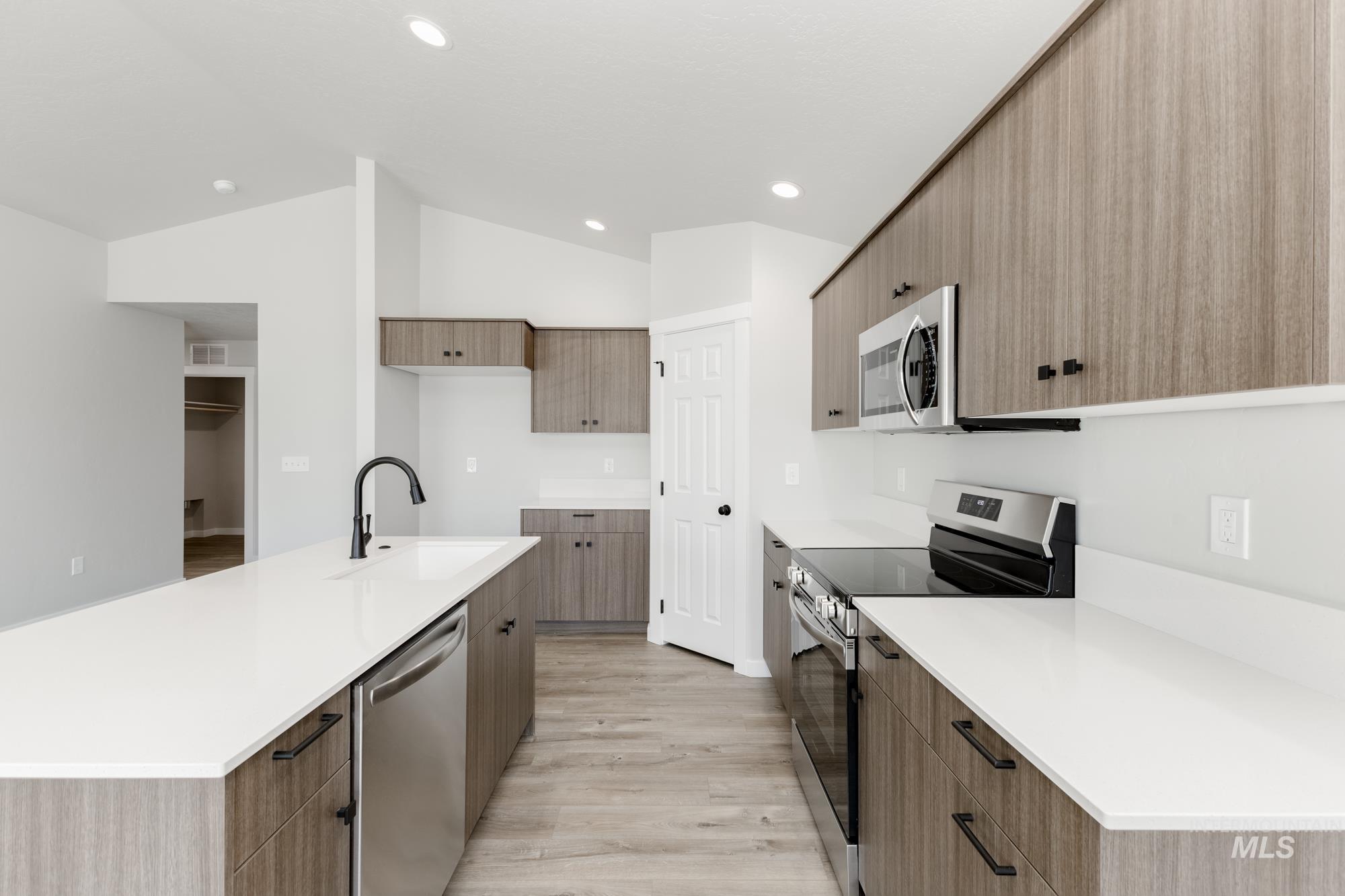 Kitchen featuring appliances with stainless steel finishes, light wood-style floors, modern cabinets, a center island with sink, and recessed lighting