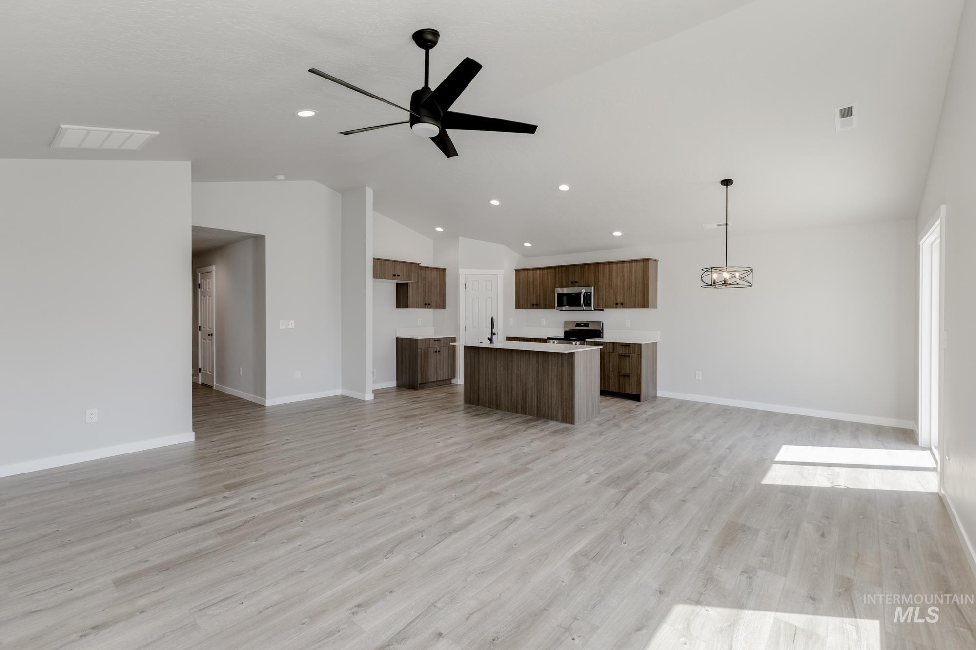 Unfurnished living room with vaulted ceiling, light wood-style flooring, ceiling fan, a chandelier, and recessed lighting