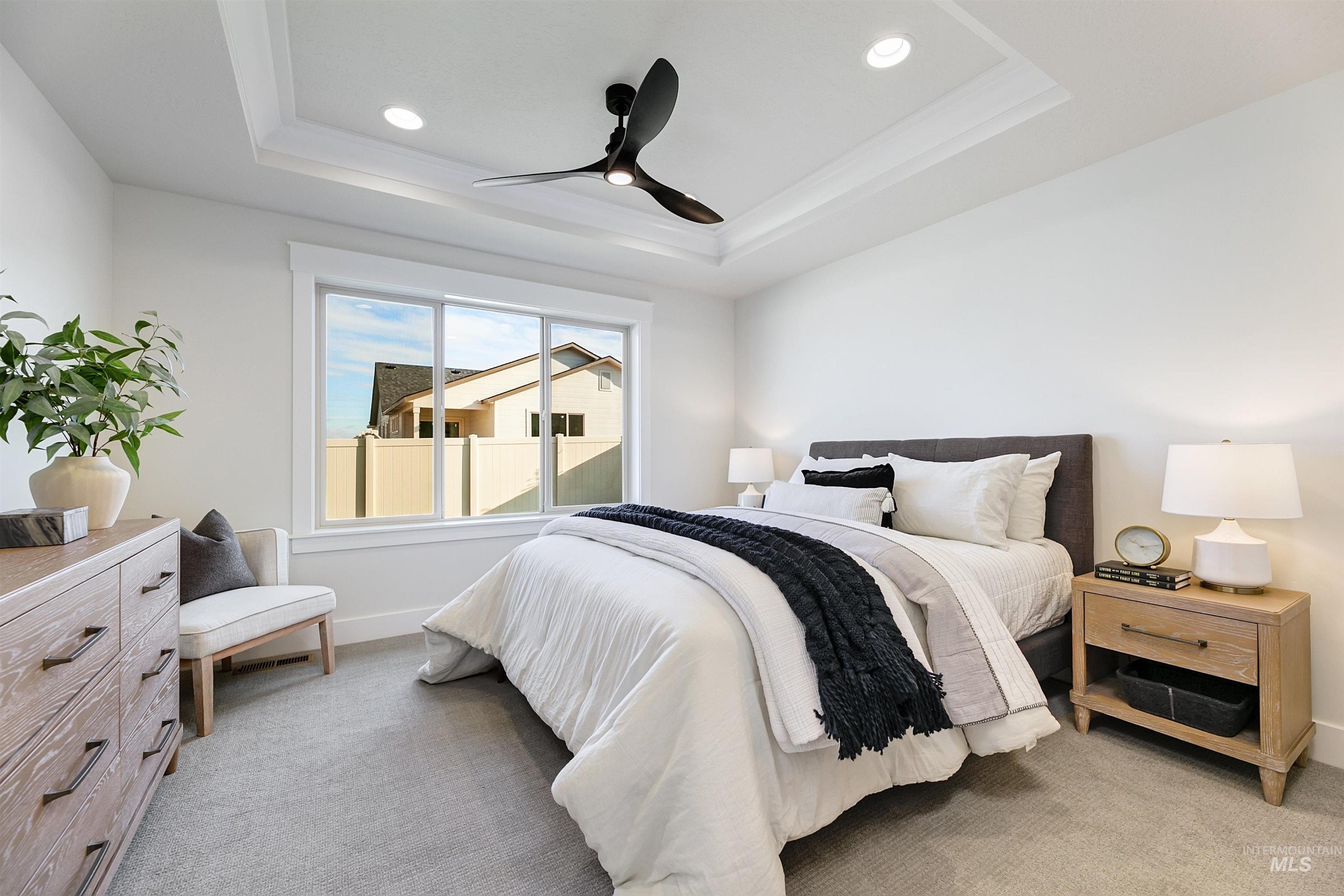 Bedroom with a raised ceiling, ceiling fan, light colored carpet, and recessed lighting