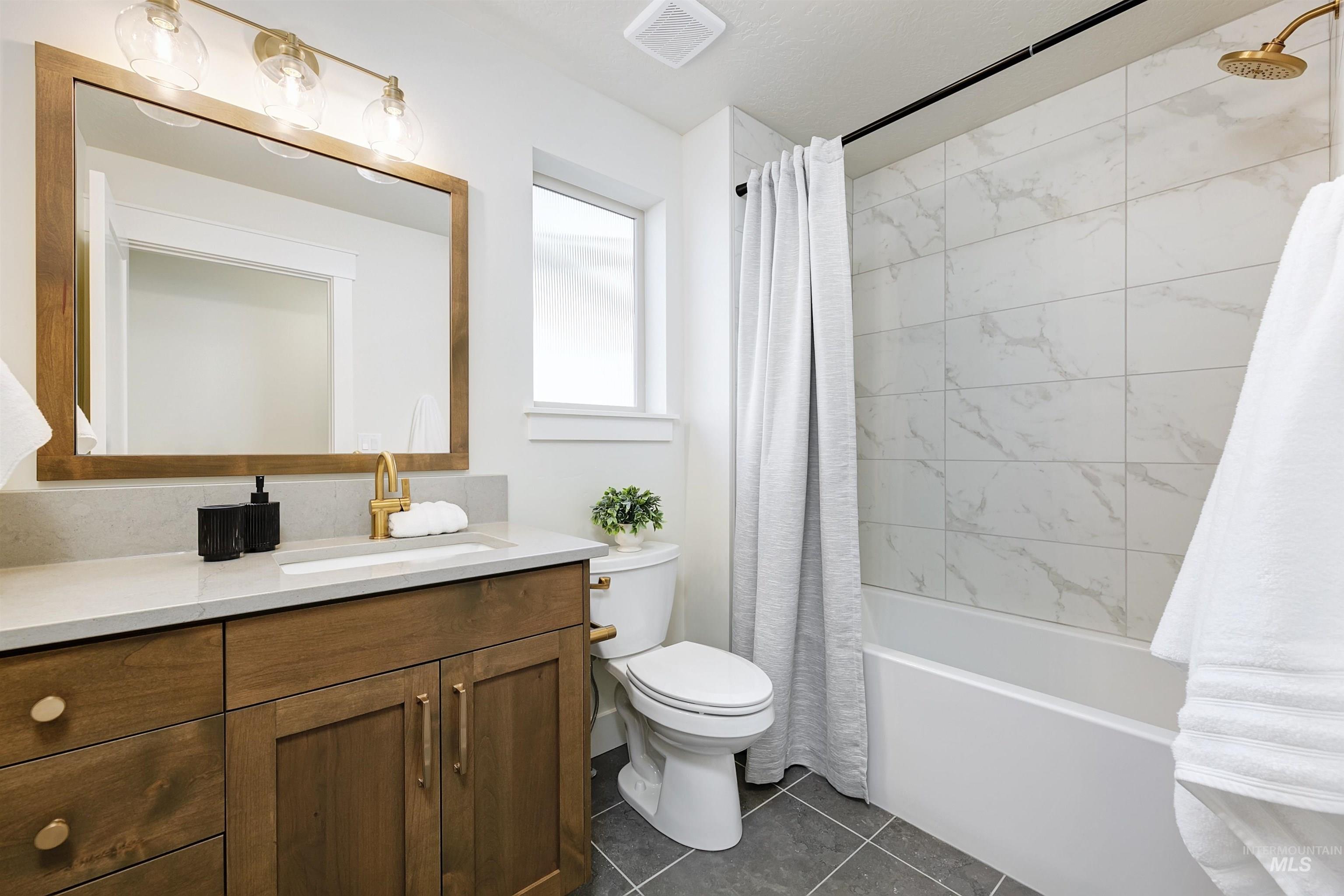 Bathroom featuring shower / tub combo with curtain, vanity, and dark tile patterned floors