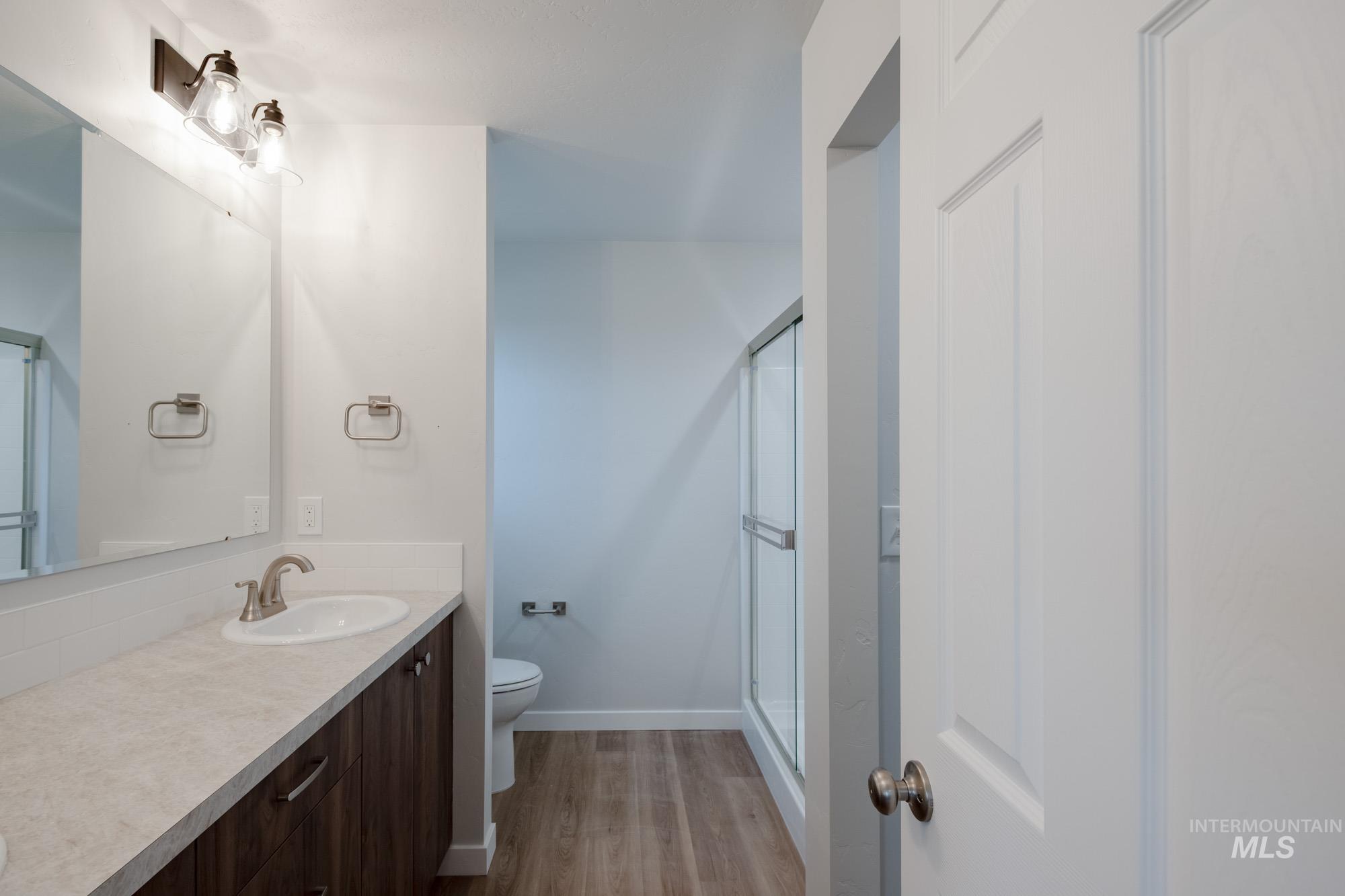 Bathroom with a stall shower, light wood-type flooring, and vanity
