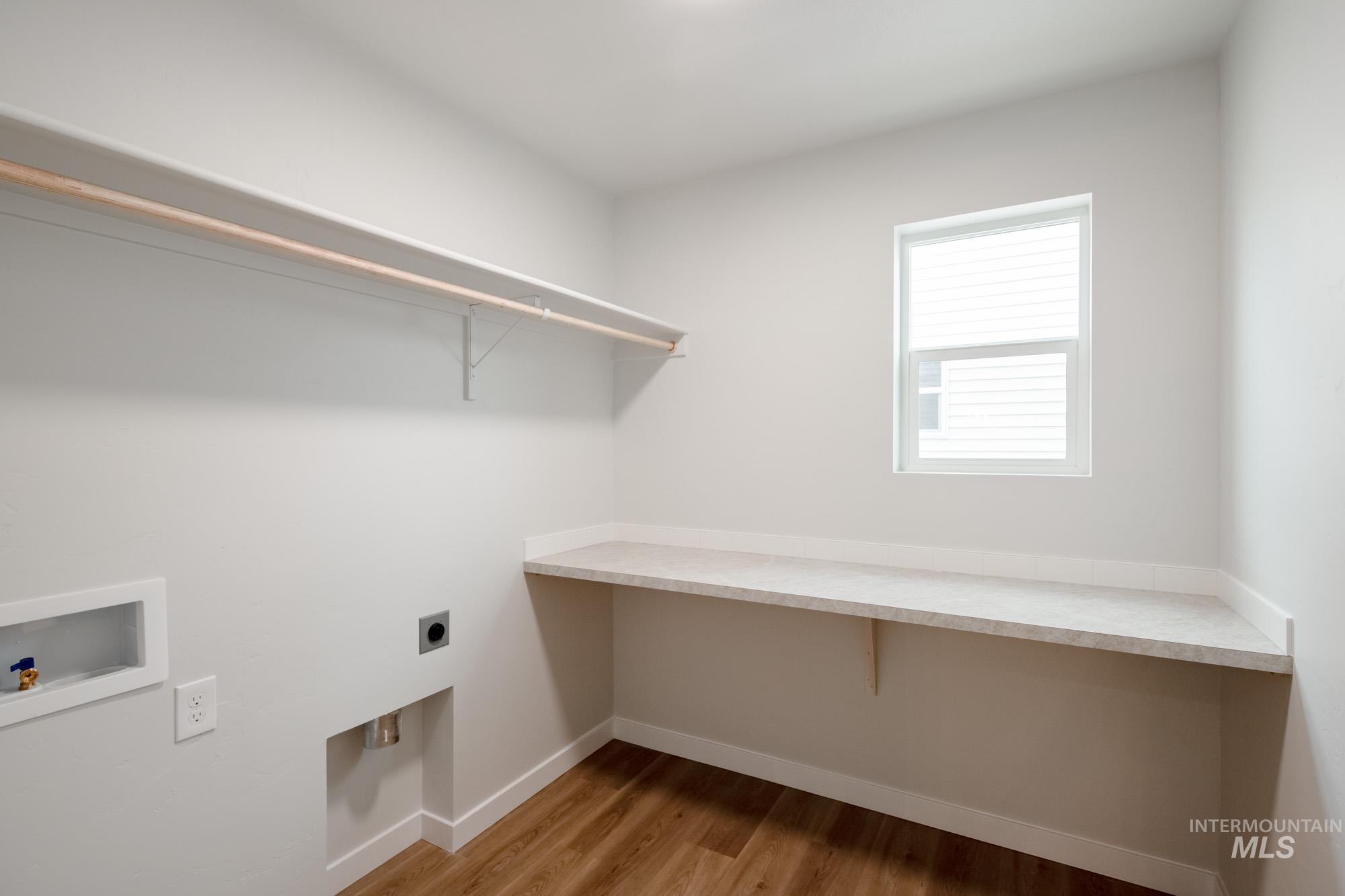 Laundry area with light wood-type flooring, hookup for a washing machine, and electric dryer hookup