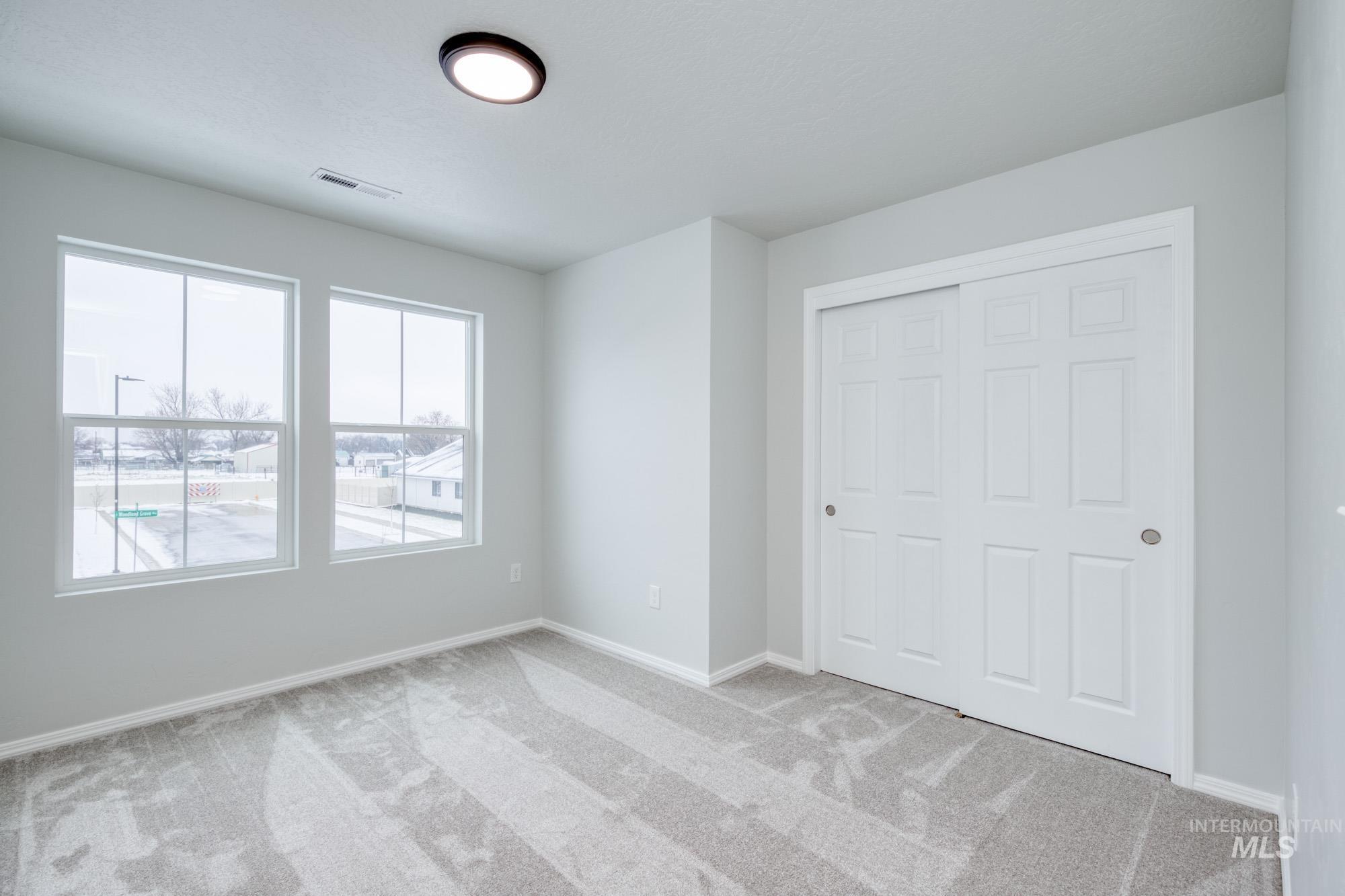 Unfurnished bedroom with light carpet and a closet