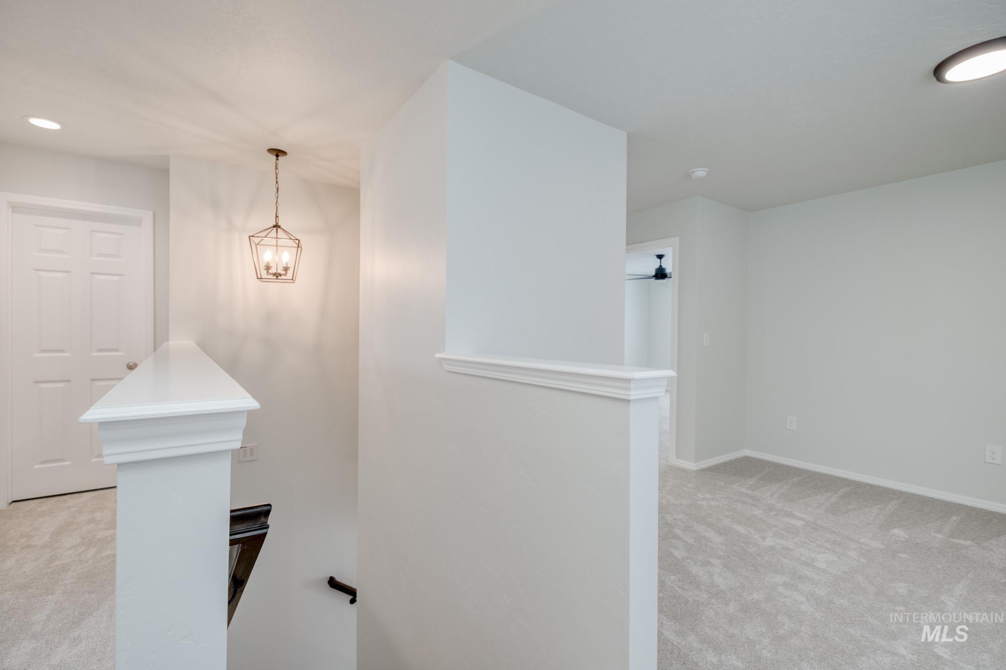 Hallway with light carpet, recessed lighting, an upstairs landing, and a chandelier