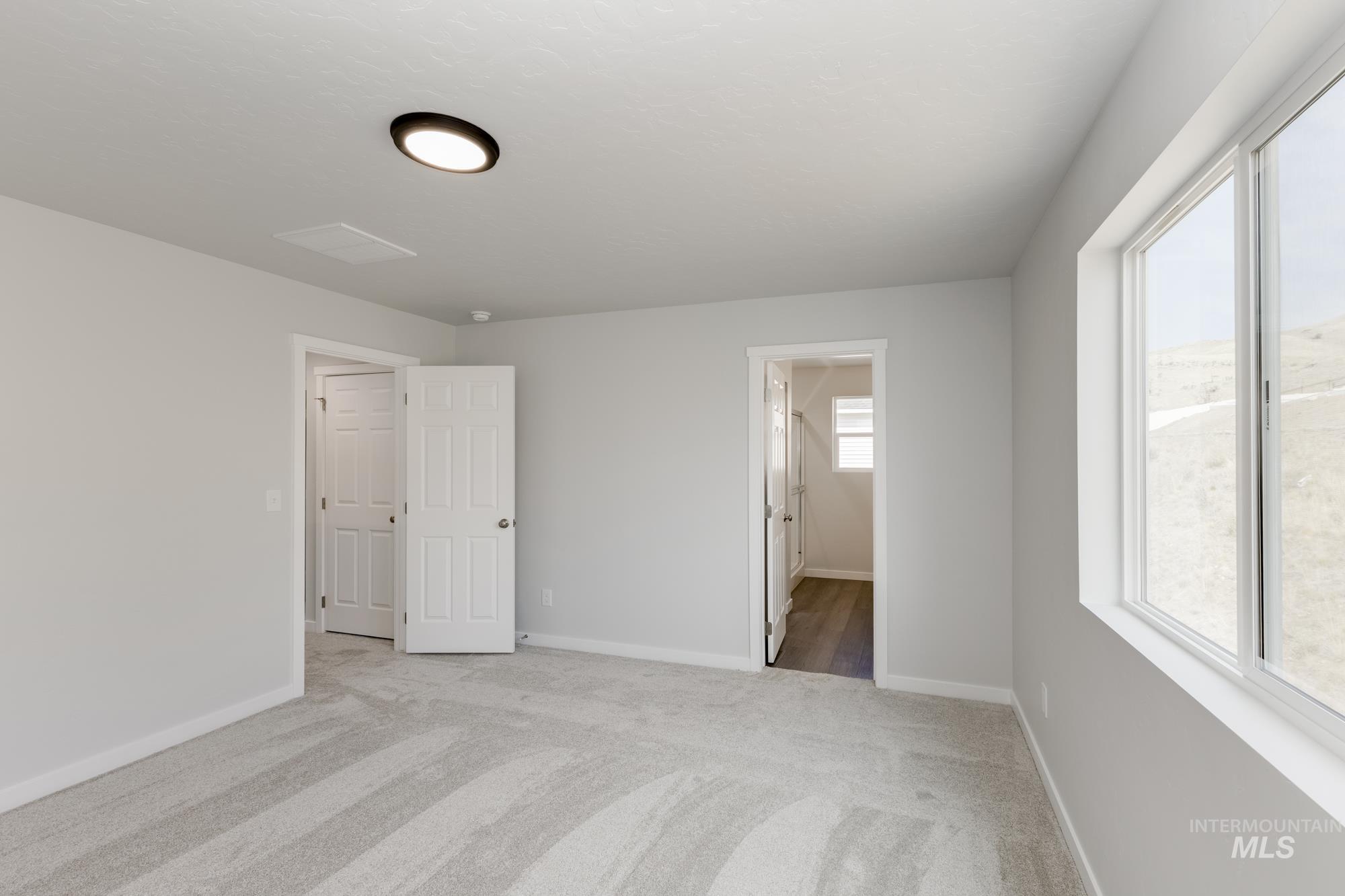 Unfurnished bedroom featuring light colored carpet and connected bathroom