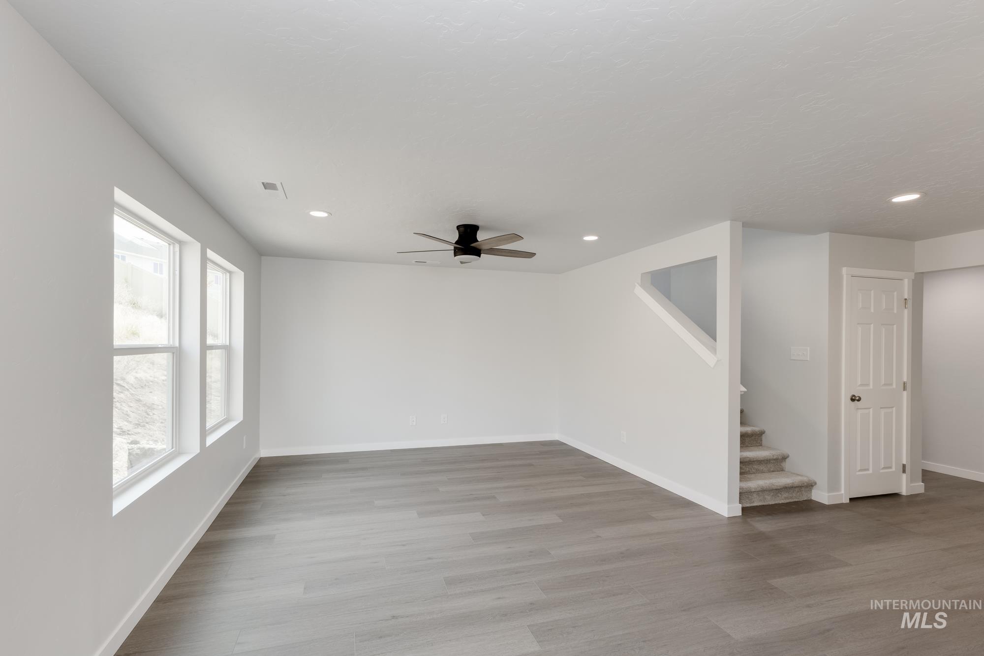 Unfurnished room with a ceiling fan, light wood-style flooring, recessed lighting, and stairway
