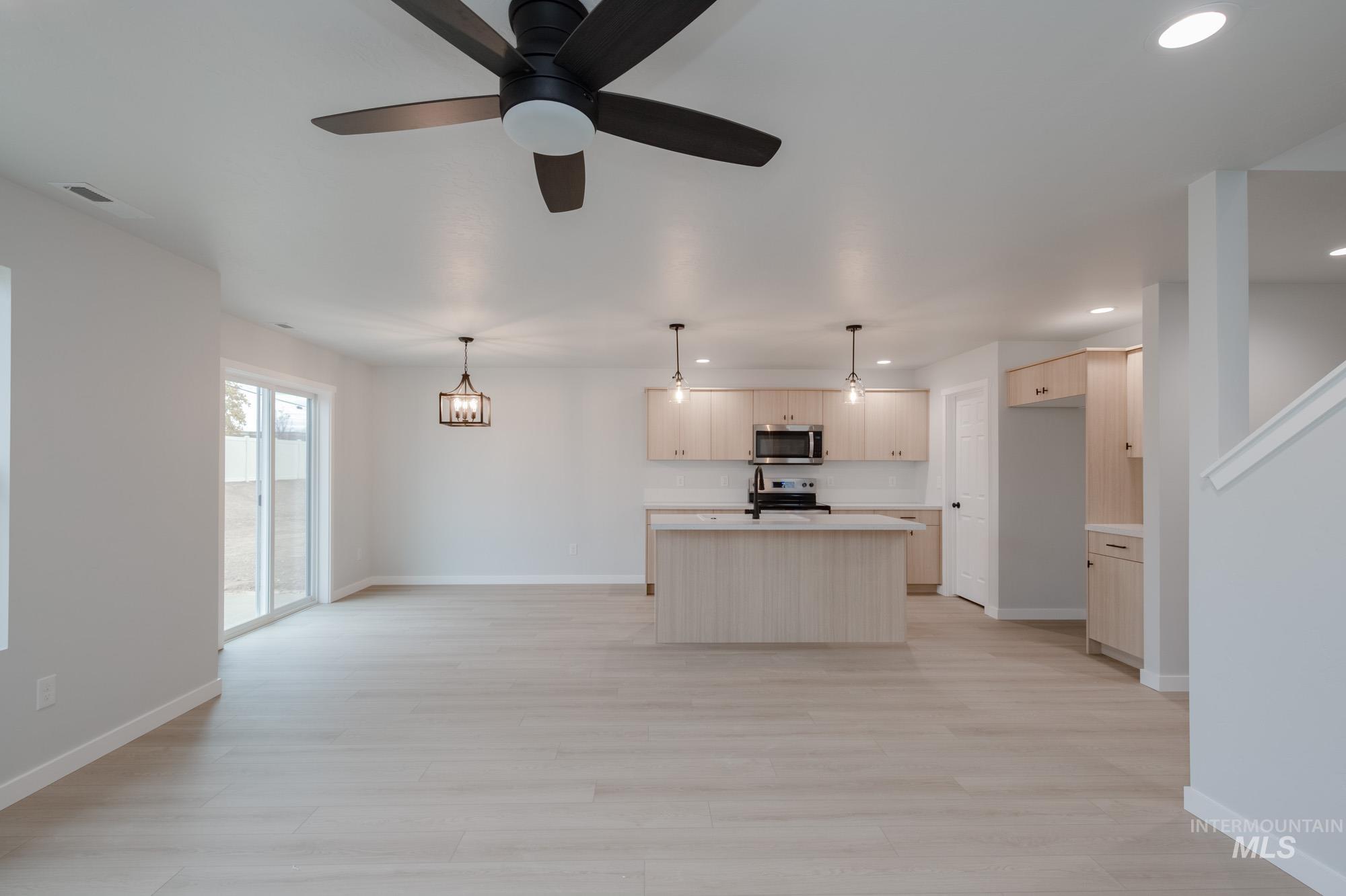 Kitchen with light countertops, a kitchen island, open floor plan, light wood-style flooring, and recessed lighting
