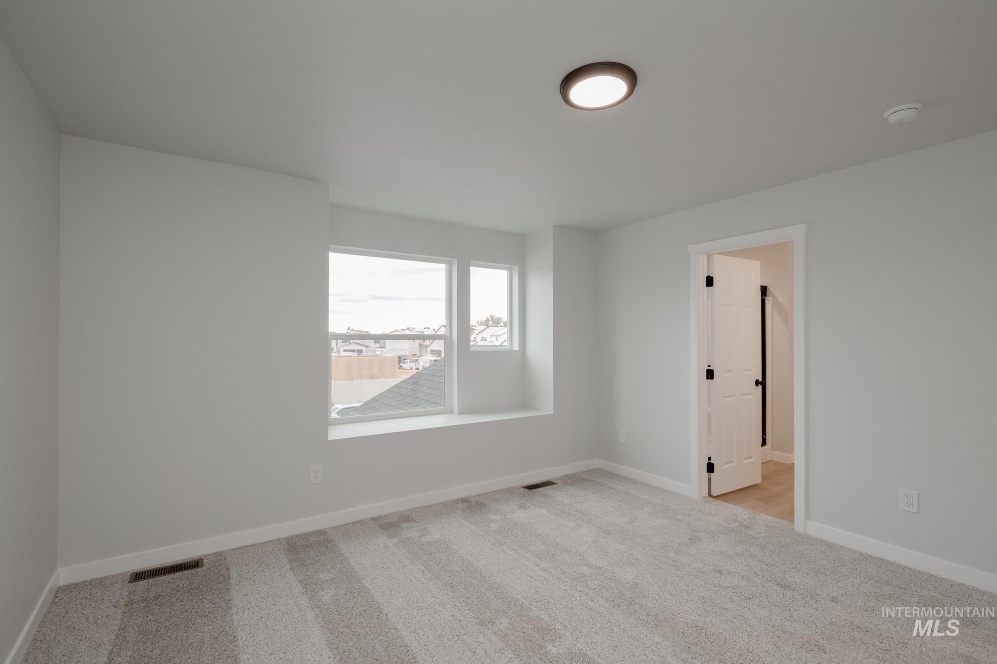 Spare room featuring light carpet and baseboards
