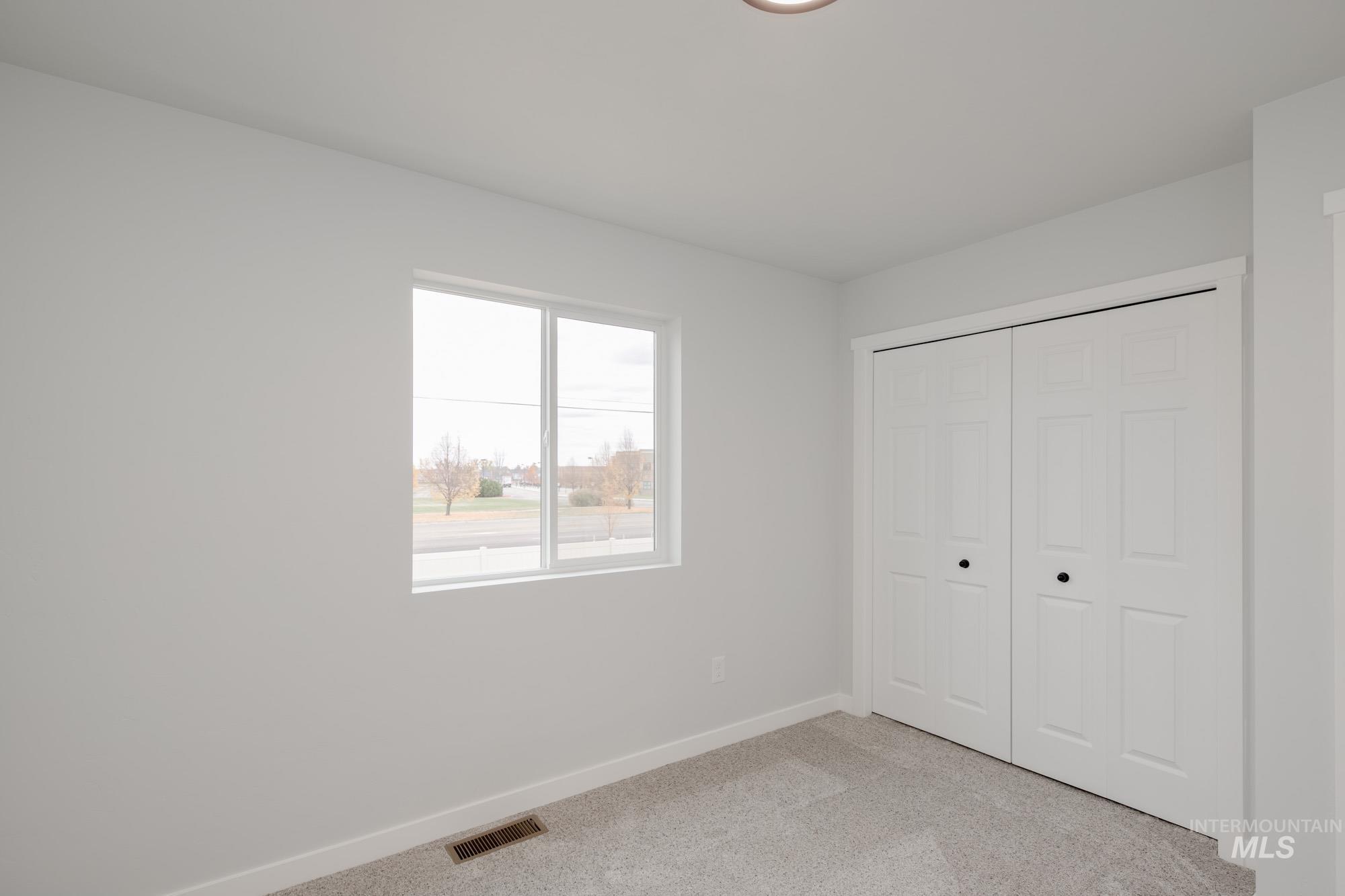 Unfurnished bedroom with light carpet and a closet