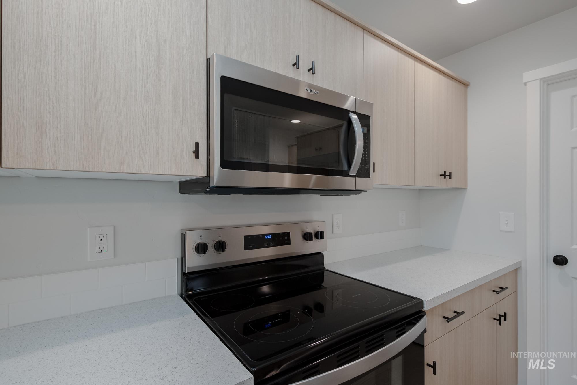 Kitchen featuring light brown cabinetry, appliances with stainless steel finishes, light stone countertops, modern cabinets, and recessed lighting