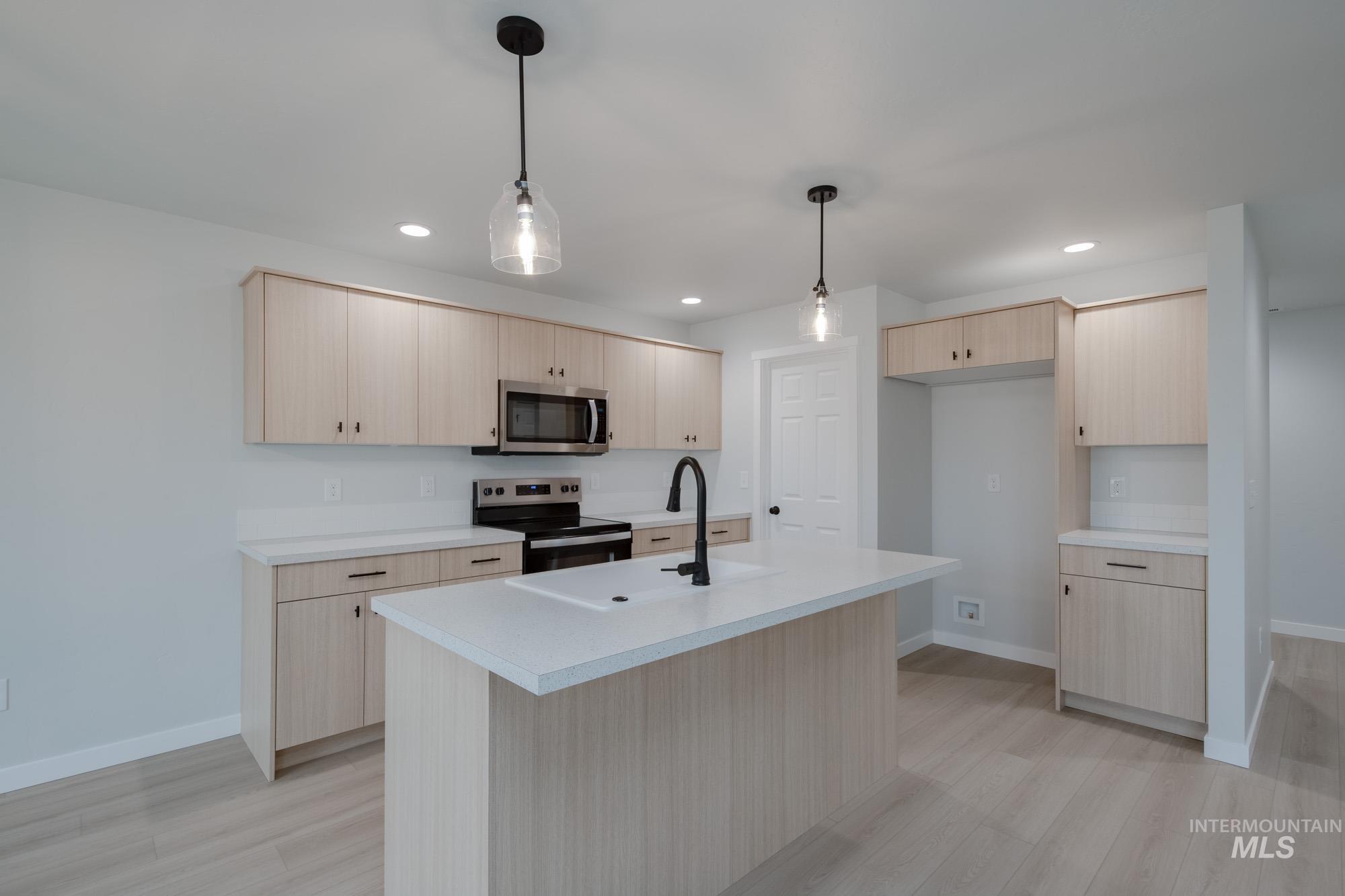 Kitchen featuring light brown cabinetry, light countertops, appliances with stainless steel finishes, light wood-type flooring, and recessed lighting