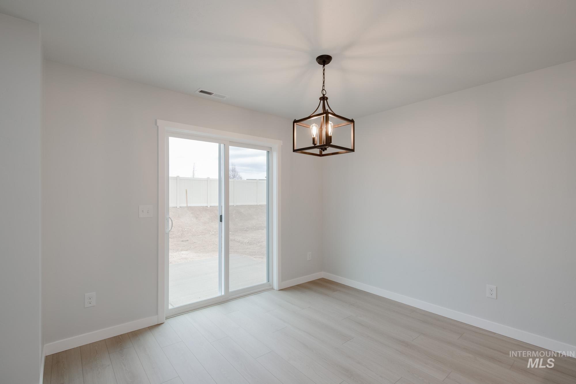 Spare room featuring light wood-style flooring and a chandelier