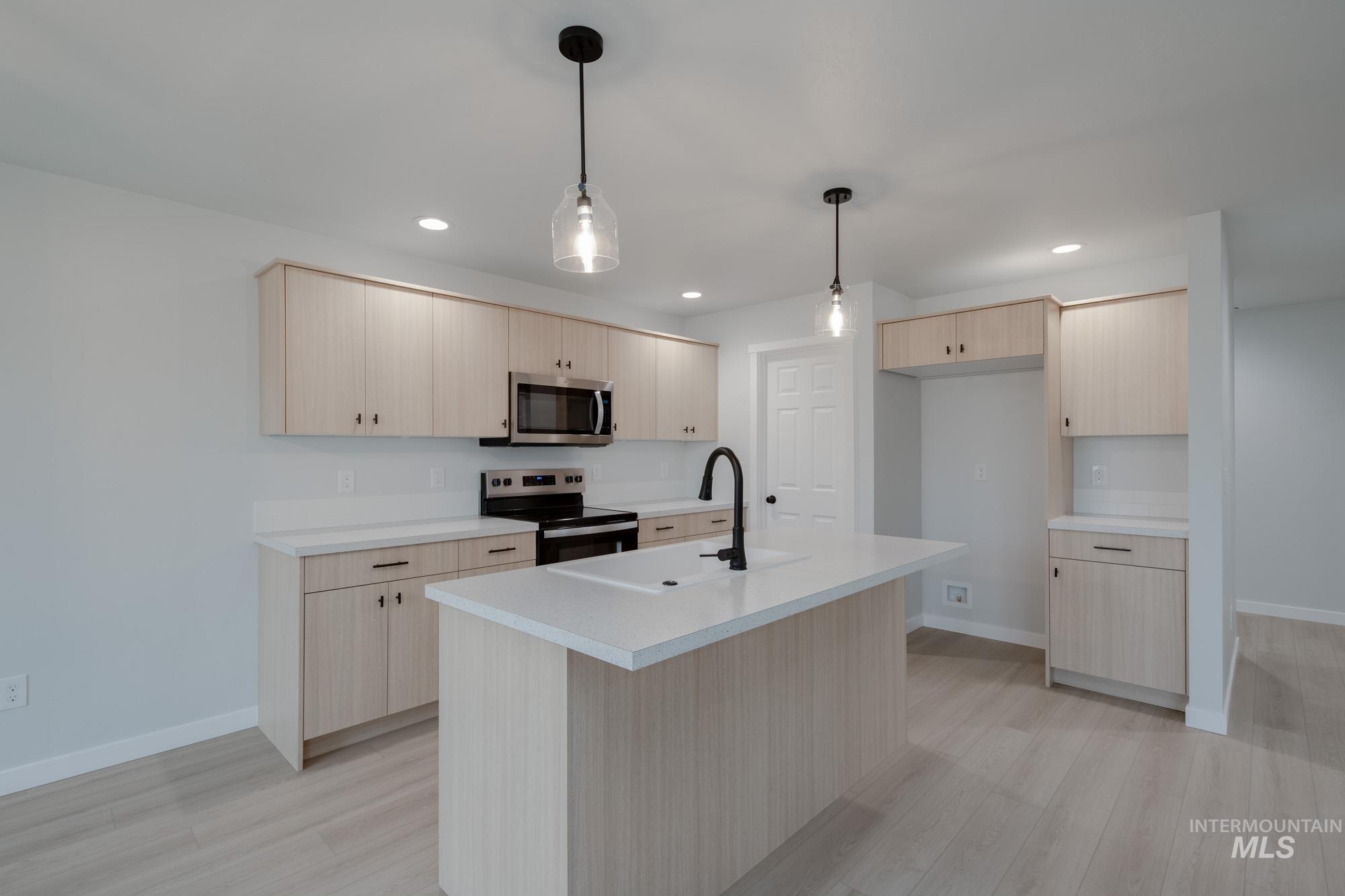 Kitchen featuring light countertops, light brown cabinets, stainless steel appliances, light wood finished floors, and recessed lighting