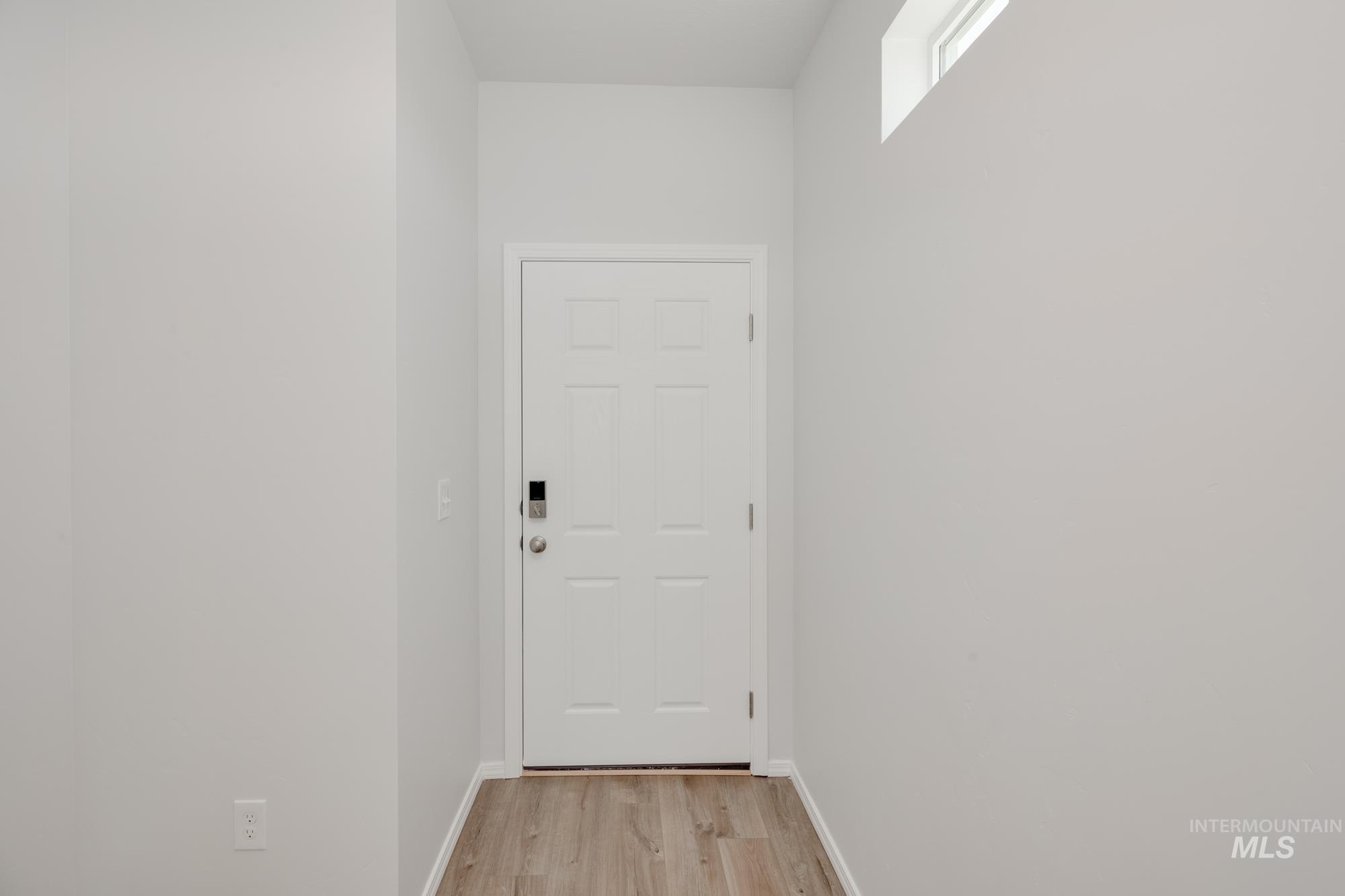 Doorway to outside with wood finished floors and baseboards